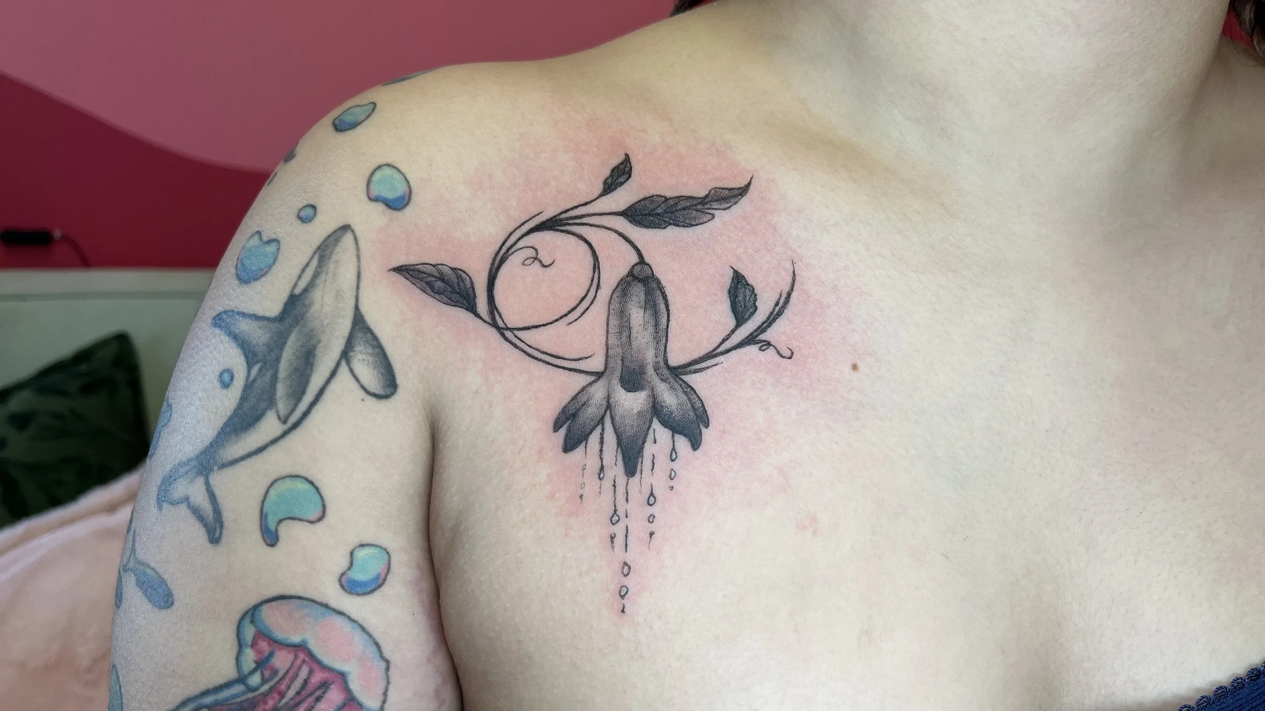 Tattoo of a moth with elongated wings and intricate details on a person's chest, surrounded by colorful spots and bubbles.