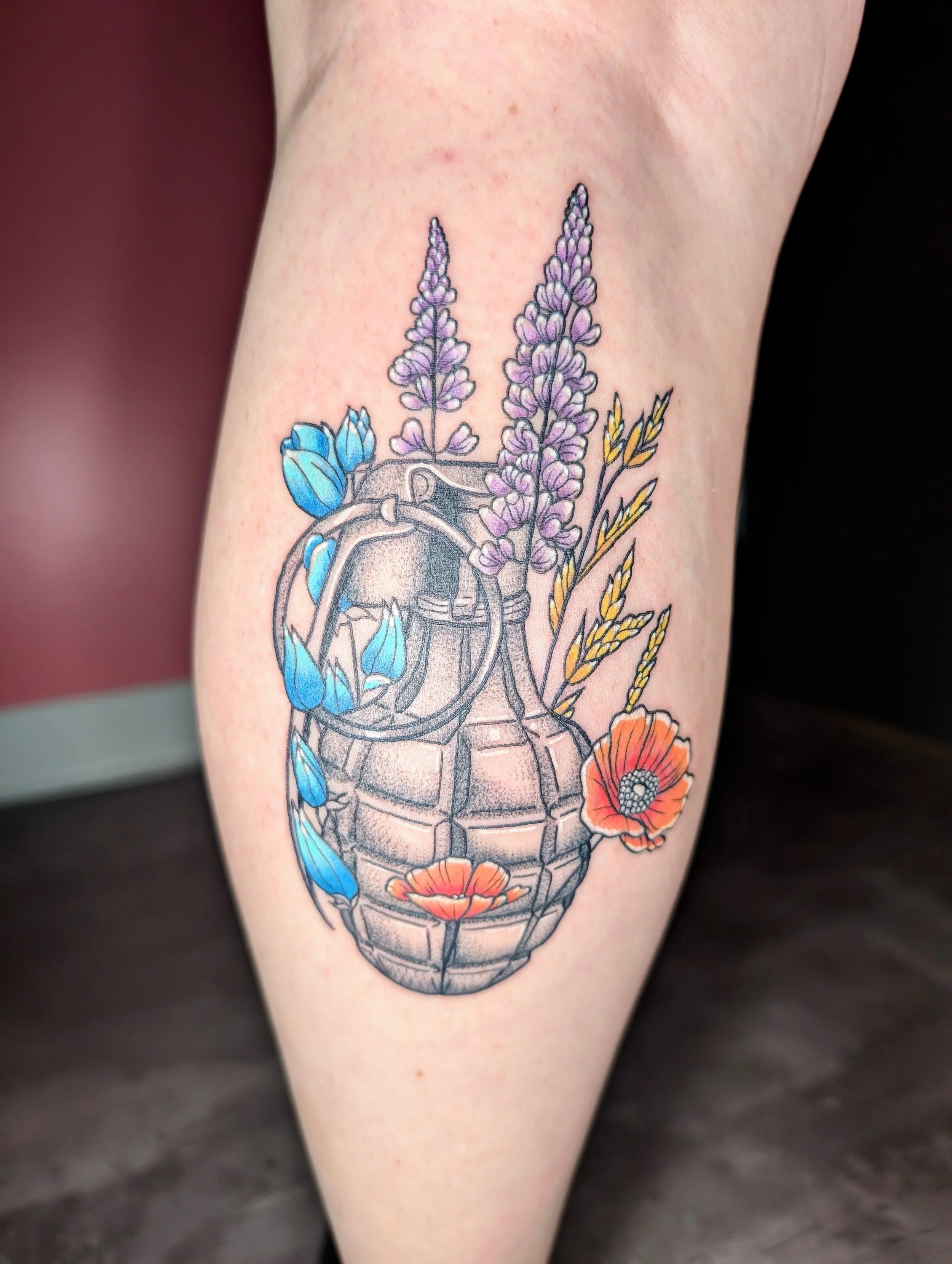 Colorful tattoo of a human heart with flowers and leaves growing from it on a person's arm.