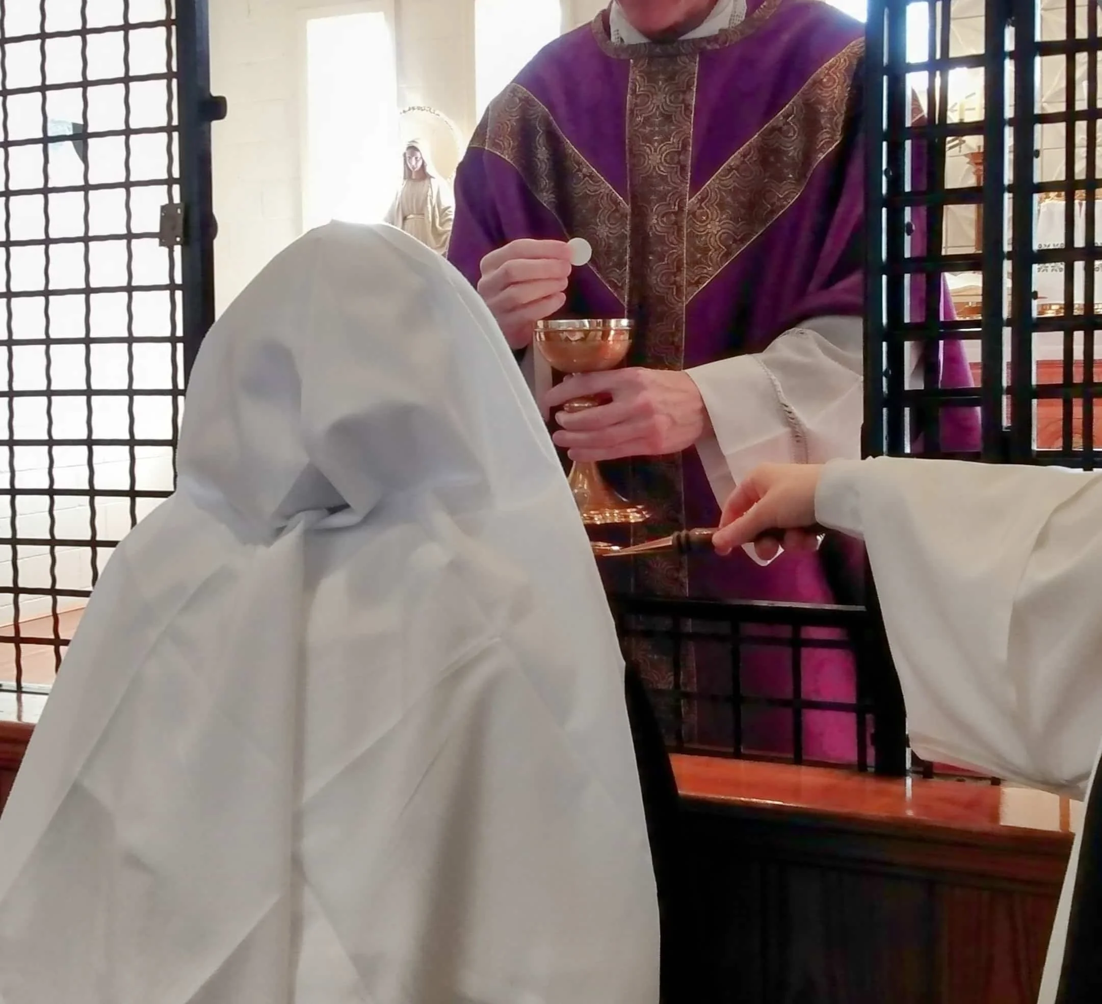 Dominican novice kneels at the altar rail to receive Holy Communion.