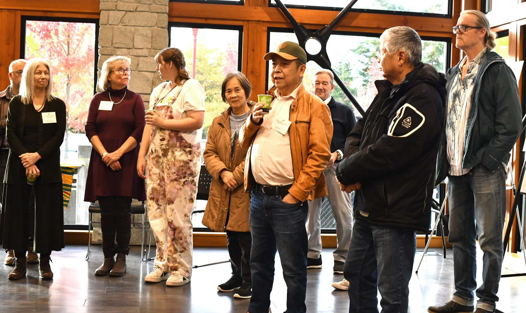 A group of future Esquimalt Village Cohousing members standing and watching a presentation about the community