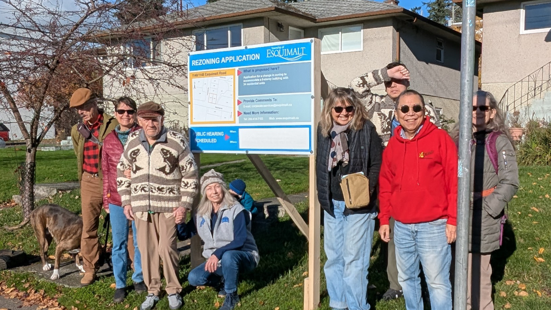 Members of Esquimalt Village Cohousing standing in front of the rezoning application sign at the future home site