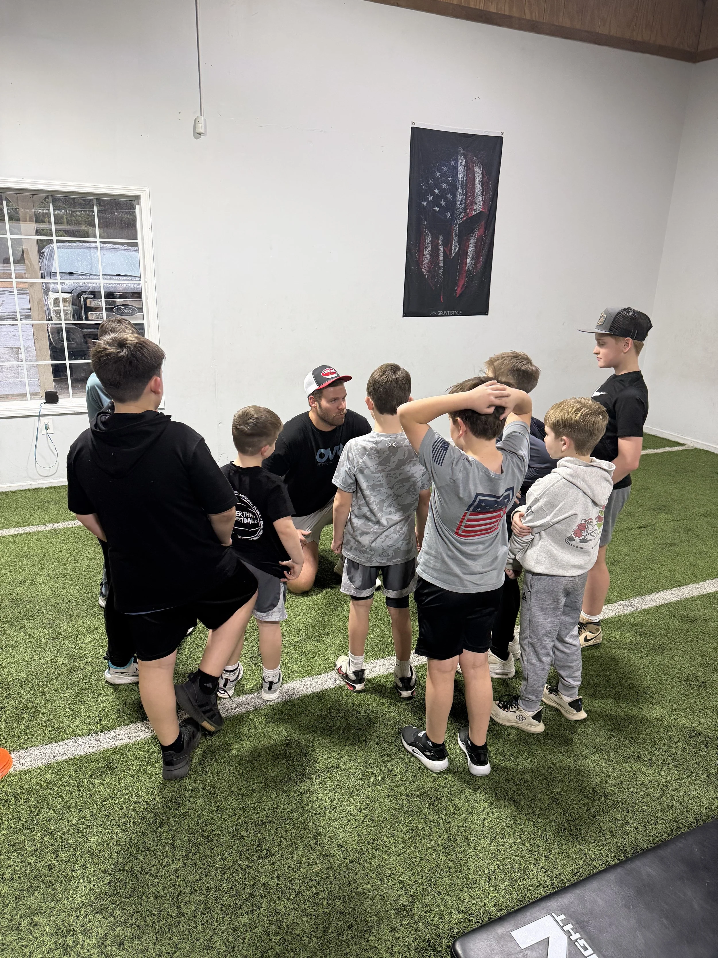 Youth class athlete group huddle with Coach Jackson.