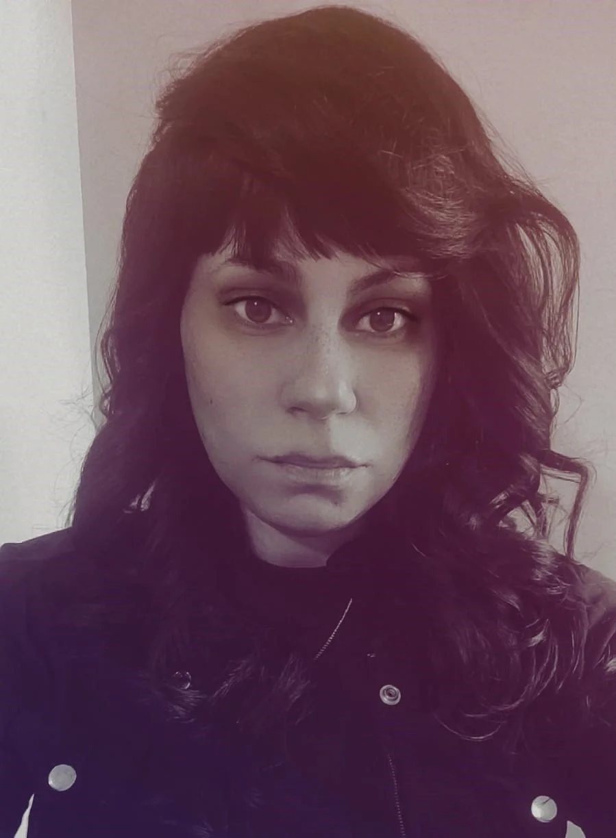 Retrato de uma mulher com cabelos cacheados escuros, expressão séria, rosto pálido.