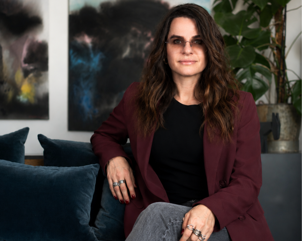Anna Arehov, grundare av Hemisfär, sitter i en harmonisk vardagsrumsmiljö omgiven av gröna växter och modern konst – en miljö som speglar hennes skandinaviska inredningsfilosofi.