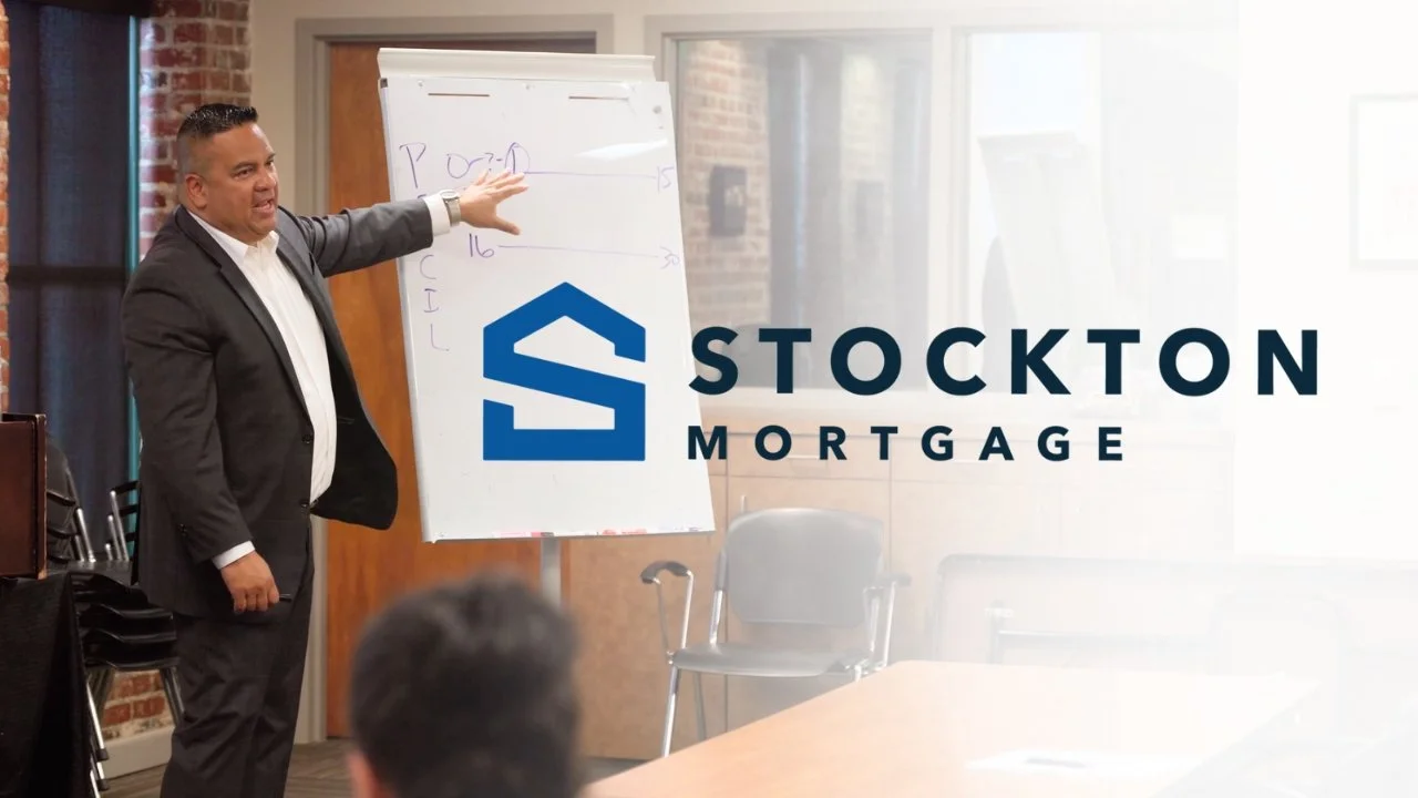 Business professional giving a presentation in a conference room with a whiteboard, with the logo and name 'Stockton Mortgage' displayed over the scene.