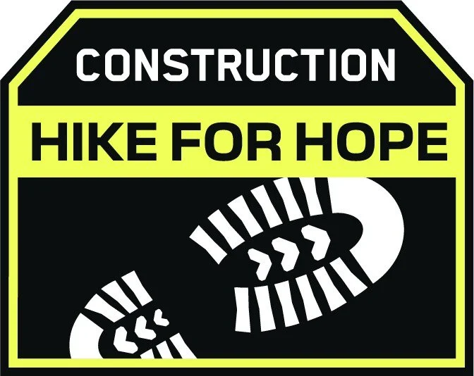 Sign with black background, outlined in yellow. Top text says 'CONSTRUCTION' in white, centered. Middle text says 'HIKE FOR HOPE' in bold yellow. Bottom shows a stylized hiking boot print in white.