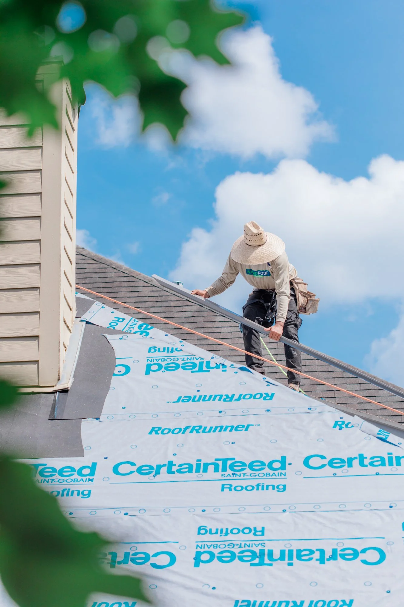 Roofer standing on roof holding a metal beam working on a roof replacement