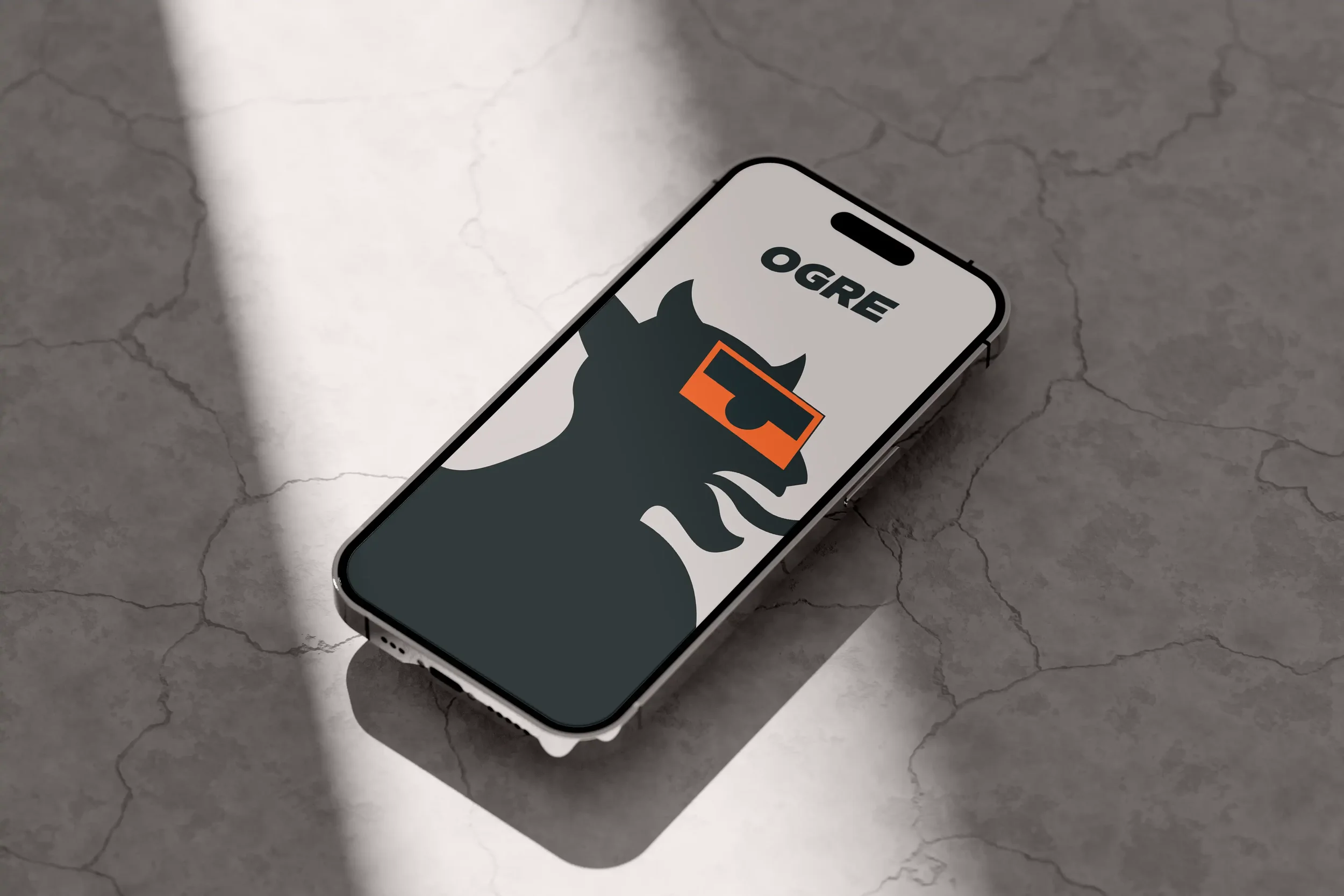 Une smartphone reposant sur une surface en béton avec une image d'un ogre portant des lunettes de soleil à l'écran, le mot 'OGRE' écrit en haut.