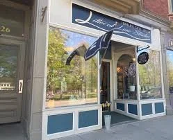 Storefront with blue and white awning, large window, and outdoor umbrella