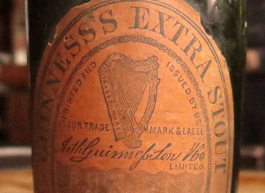 Close-up of a vintage Guiness beer label showing the harp logo and the text 'Guinness Stout Limited'.