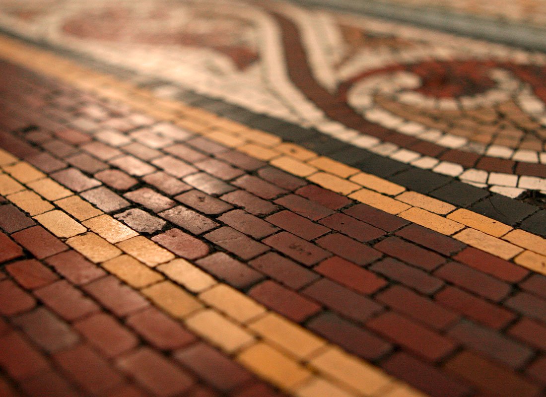 Close-up of a patterned brick floor with red, yellow, and black bricks forming curved and spiral designs.