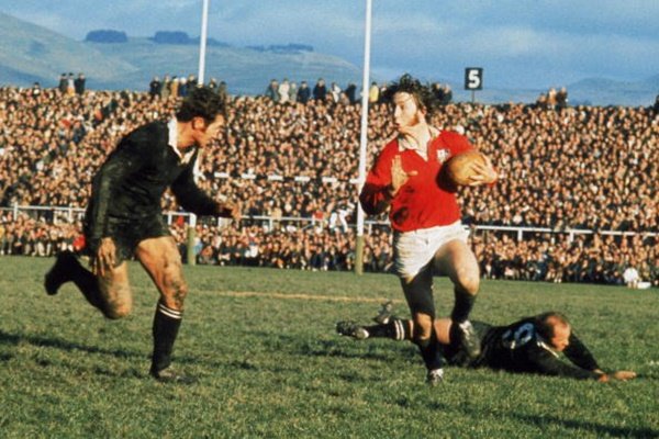 Rugby game with players in action and a large crowd in the background.