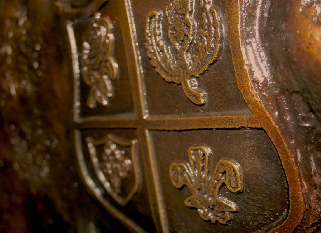 Close-up of a rusted metal surface with a crest or emblem featuring a fleur-de-lis design.