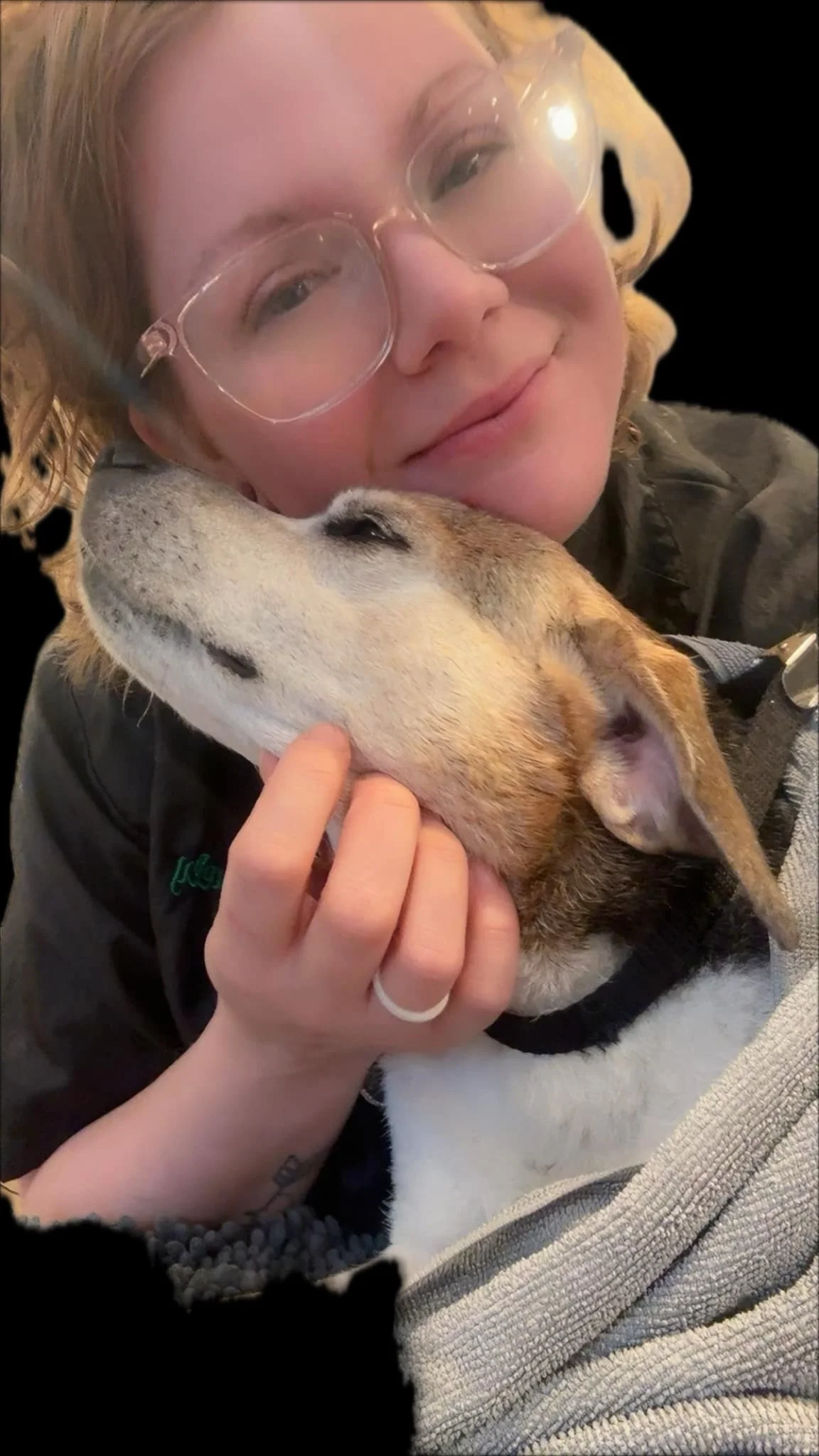 A woman with glasses cuddling a sleeping dog.