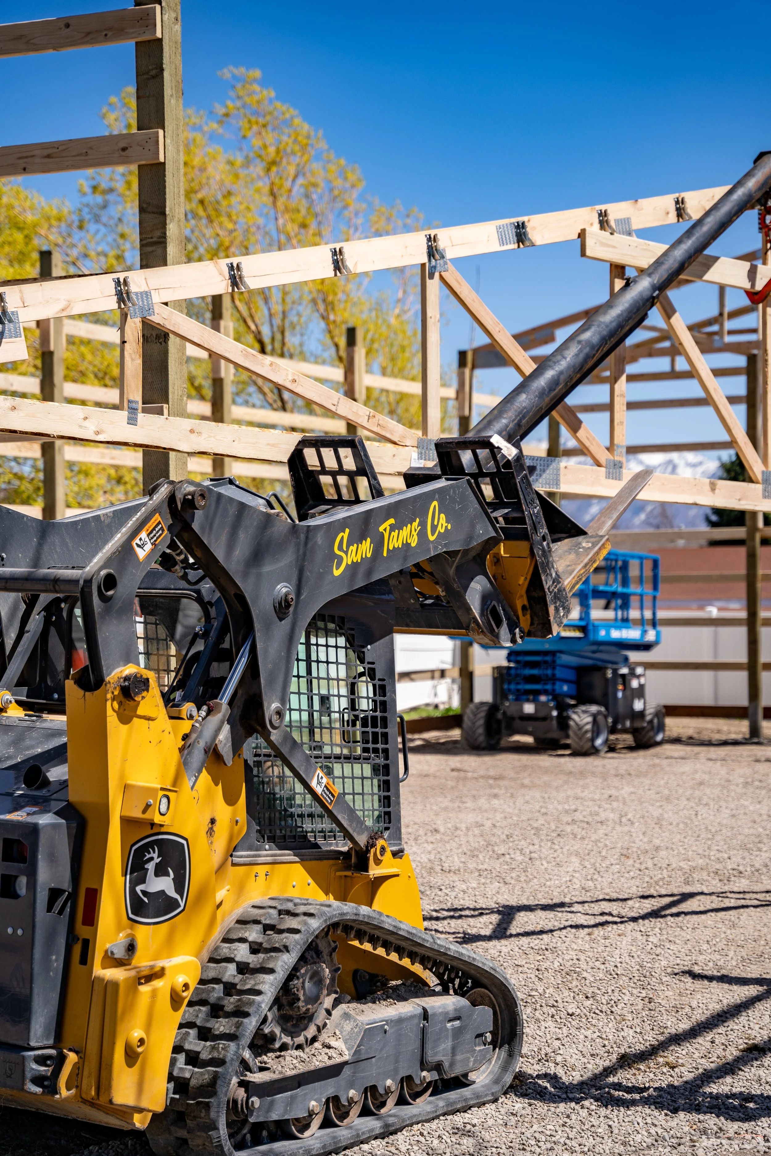 Sam Tams Co. branded skid steer on a pole barn job site in Utah with post frame construction in progress