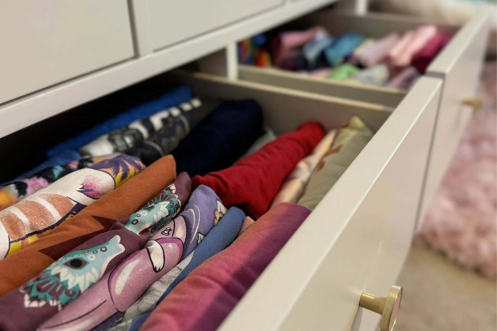 an open drawer with sorted and folded clothing in it.