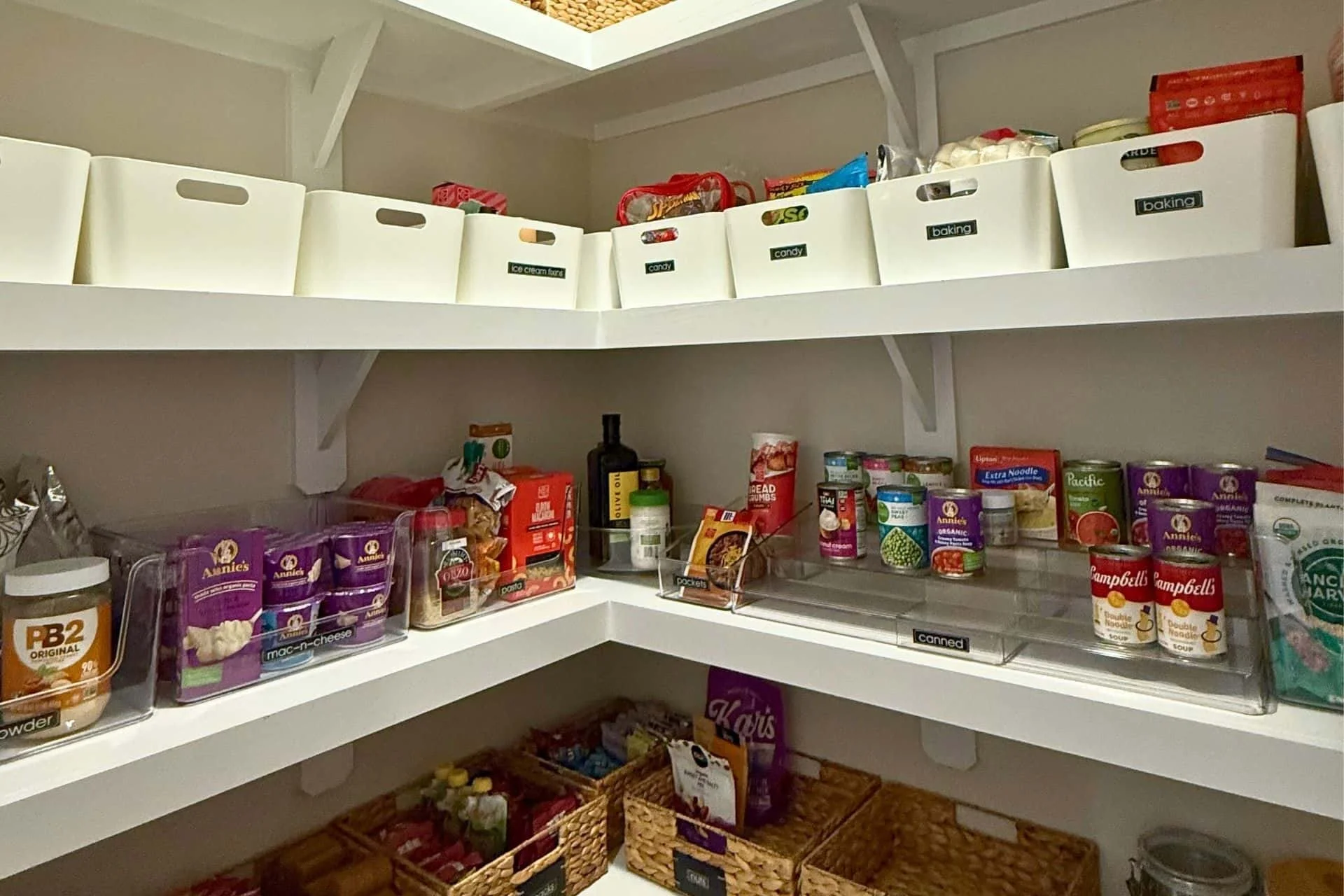 organized kitchen pantry with cans neatly stacked, labeled bins an baskets with dried goods in them