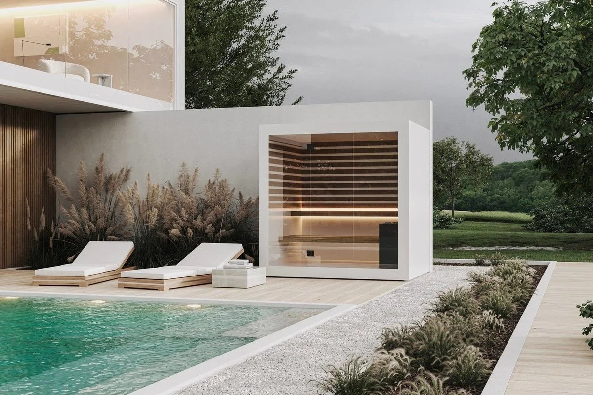 Modern backyard with a swimming pool, two white lounge chairs, a small table, a wood-paneled sauna, and landscaped greenery.