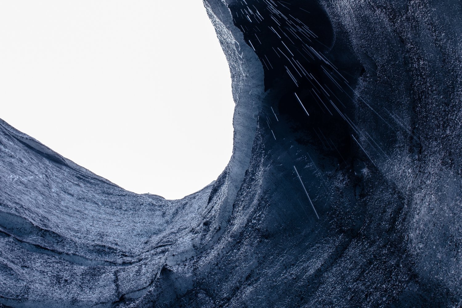 View from inside a dark, rocky cave opening to a bright sky.