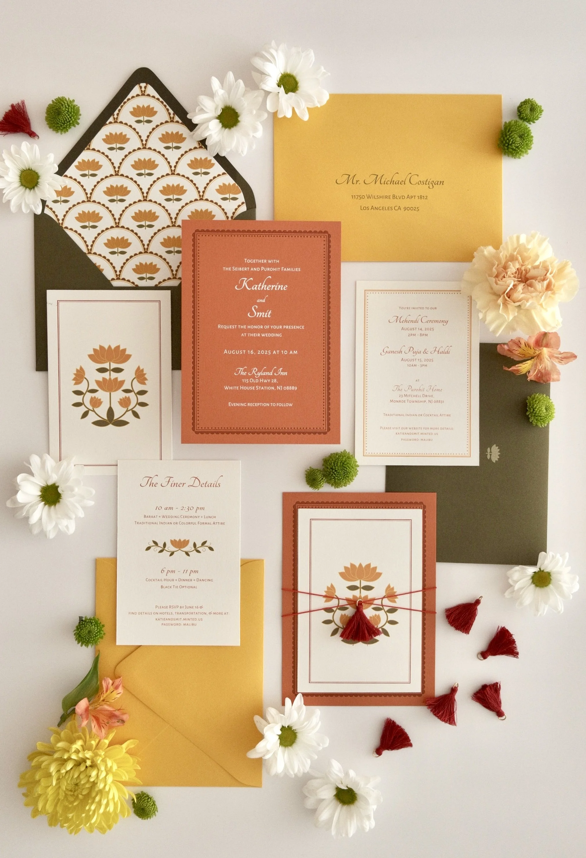Colorful Indian wedding invitation suite featuring lotus illustrations, mustard yellow envelopes, coral and olive green stationery, floral details, and tassel embellishments inspired by traditional South Asian design.