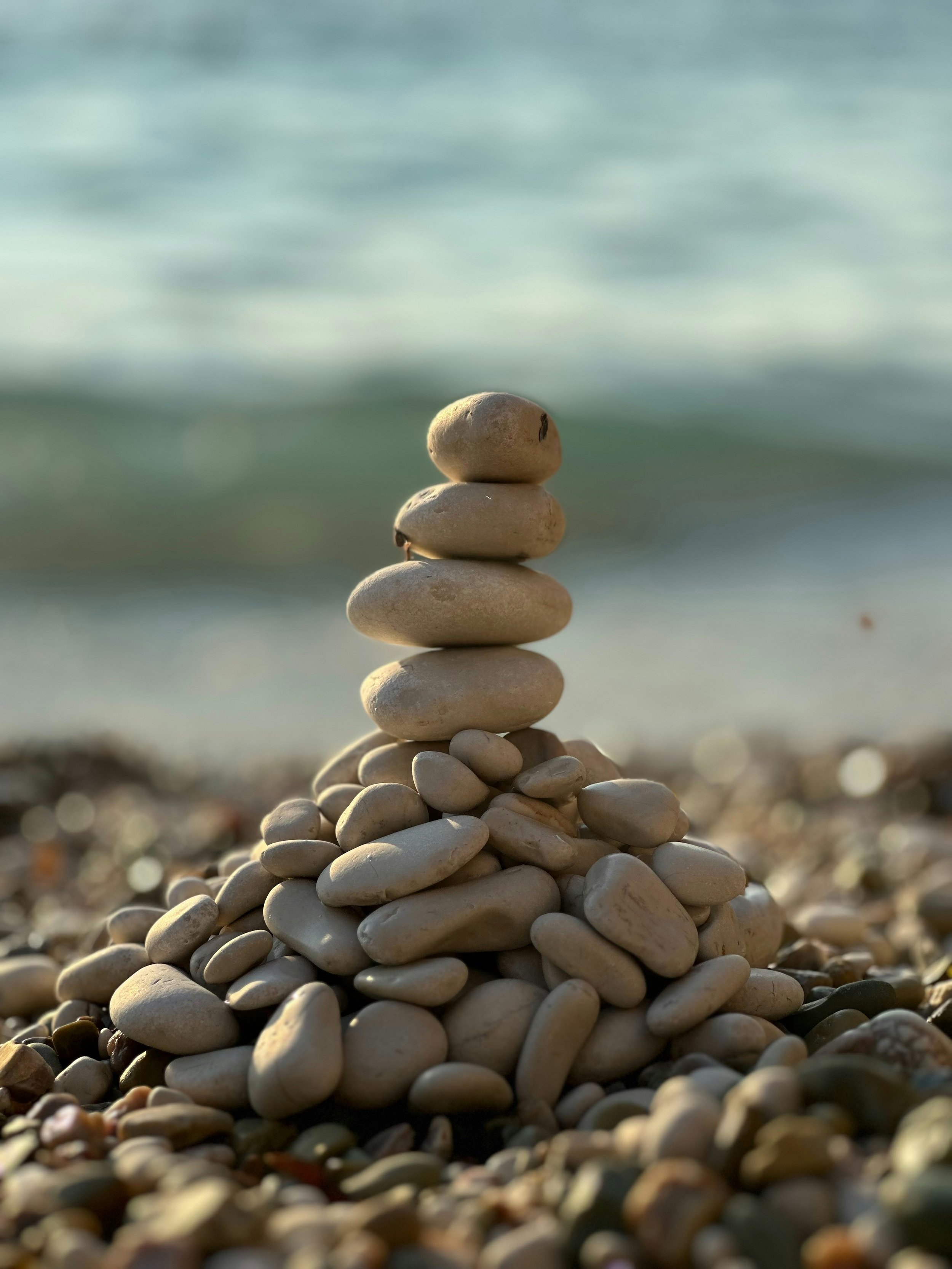 Stack of balanced rocks on a beach, symbolizing stability, resilience, and finding balance.