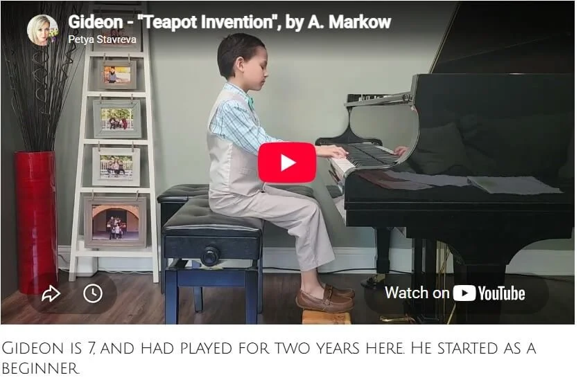 Young boy playing a black grand piano while sitting on a piano bench in a living room.