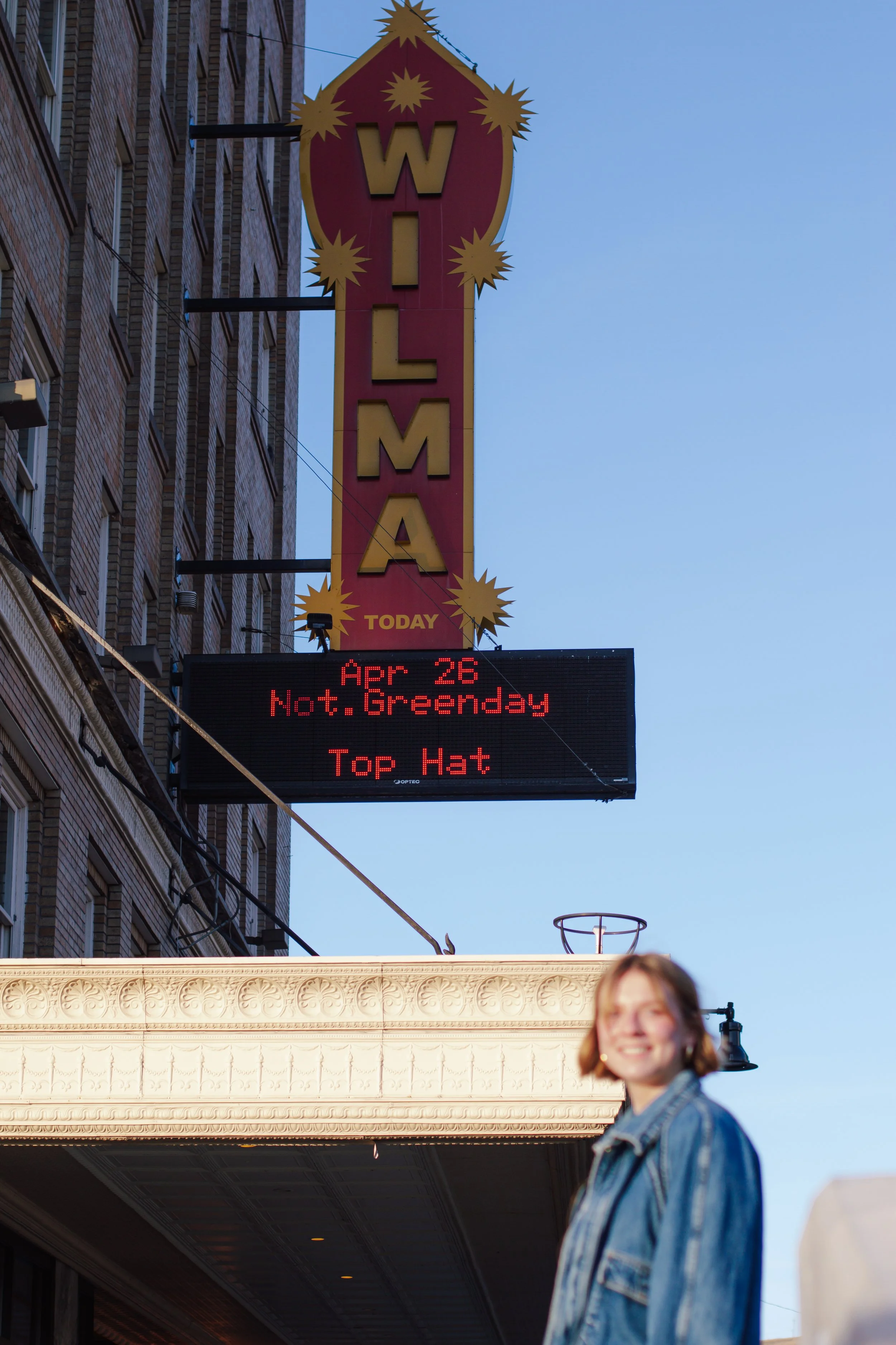 girl smiling in front of theatre sign