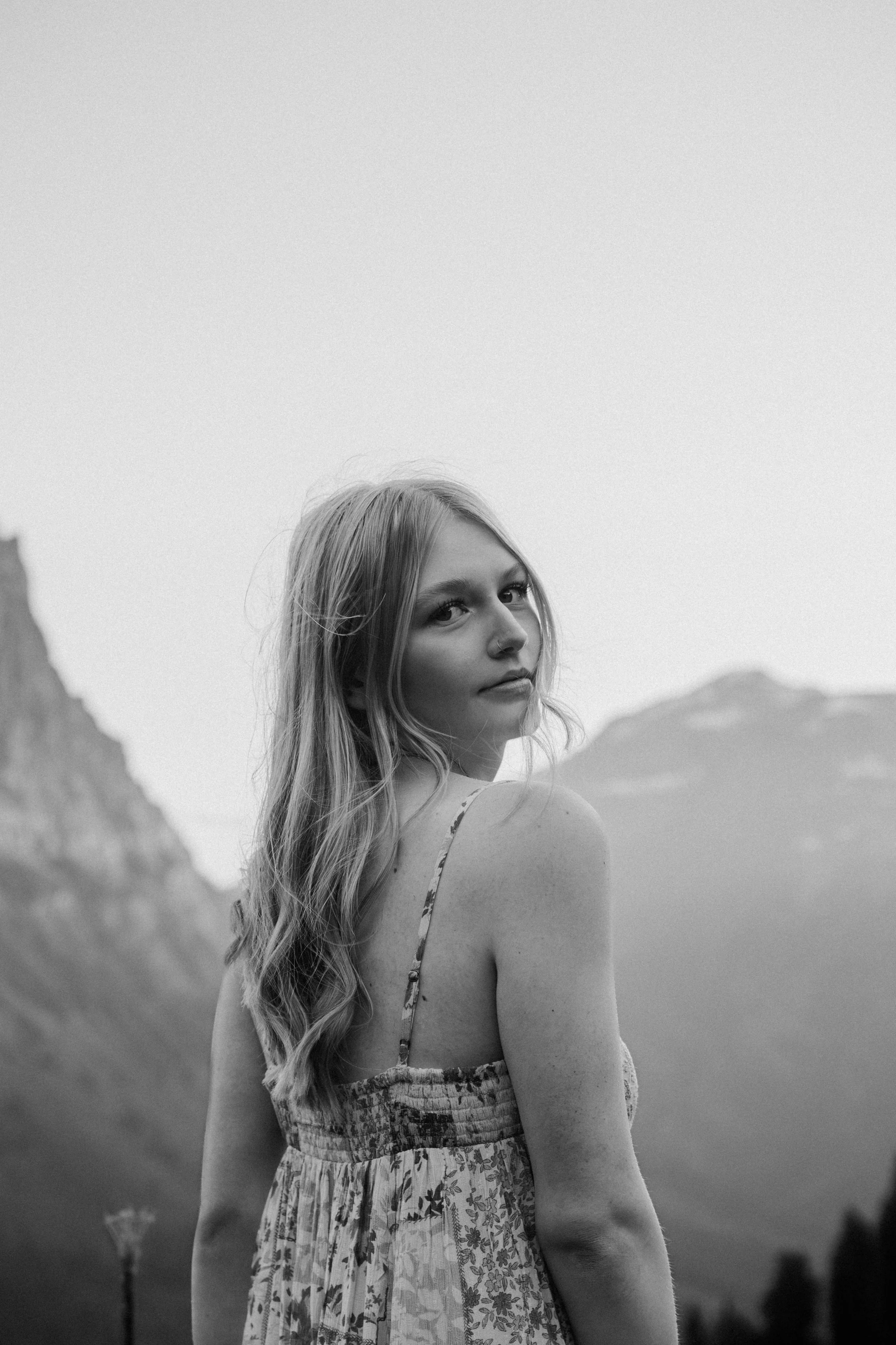 girl looks over her shoulder in front of glacier mountains