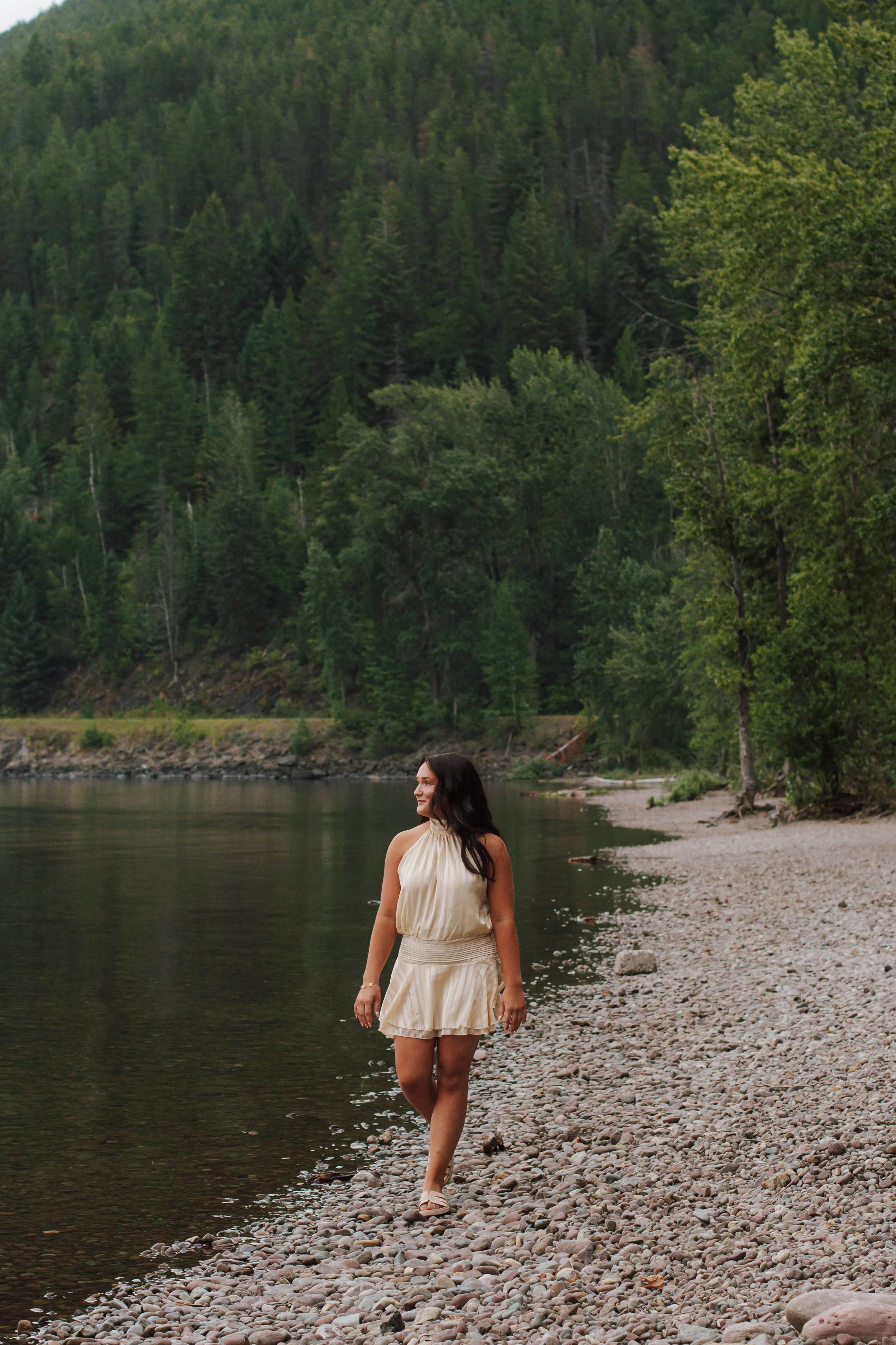 senior girl walks down shore of lake