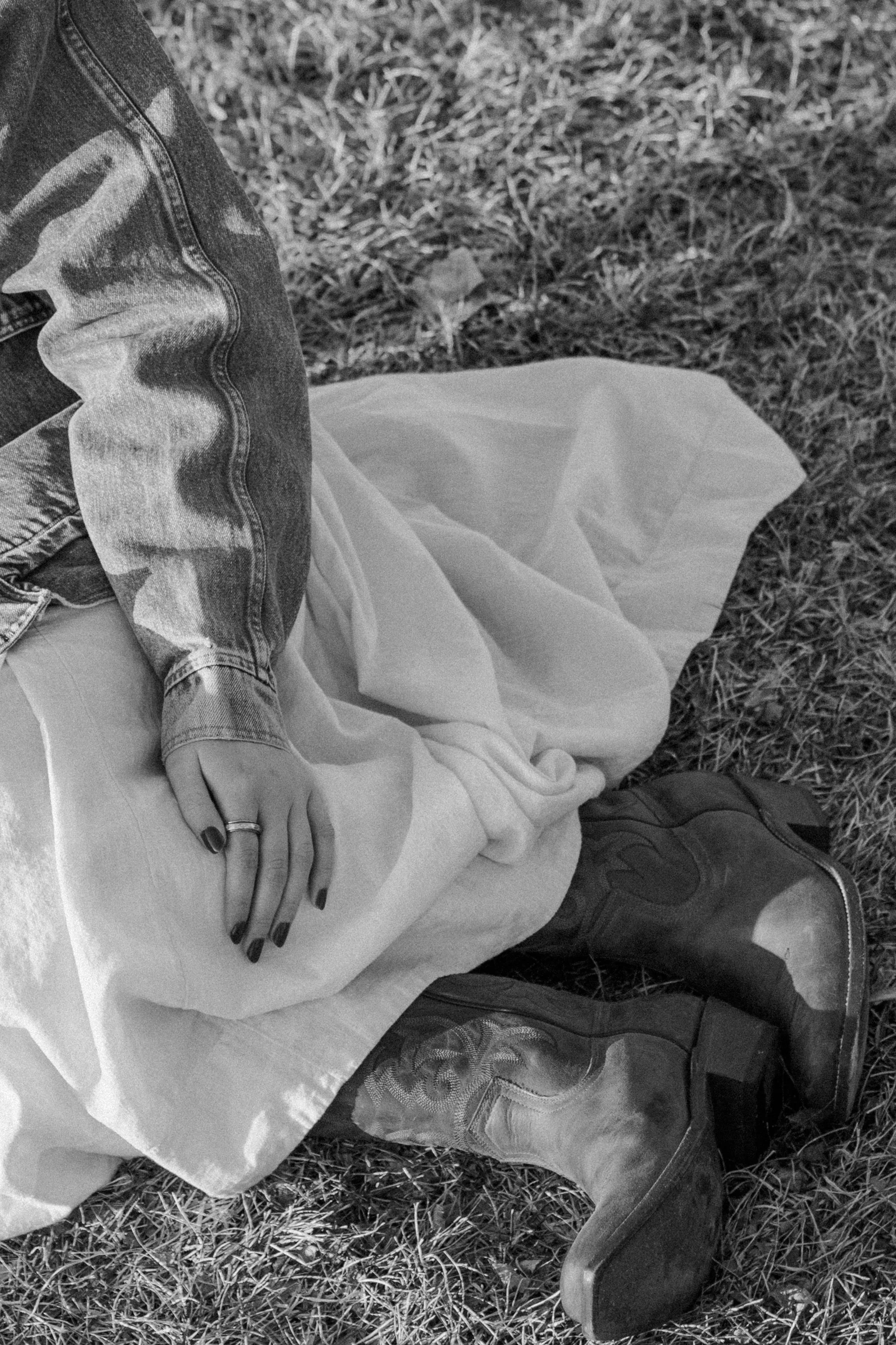 senior girls hand with ring resting on dress and cowboy boots