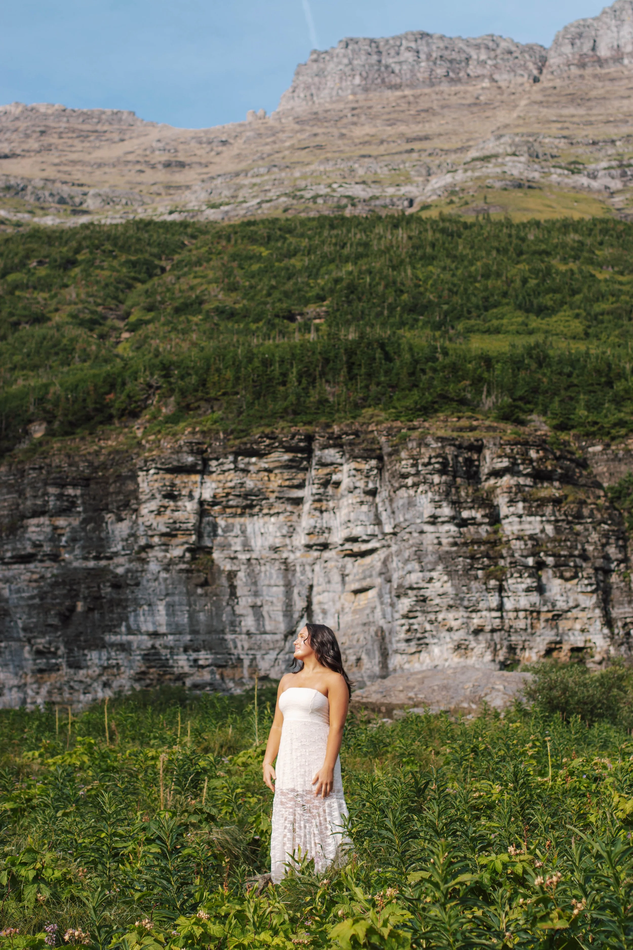 senior girl stands in front of mountains facing the side