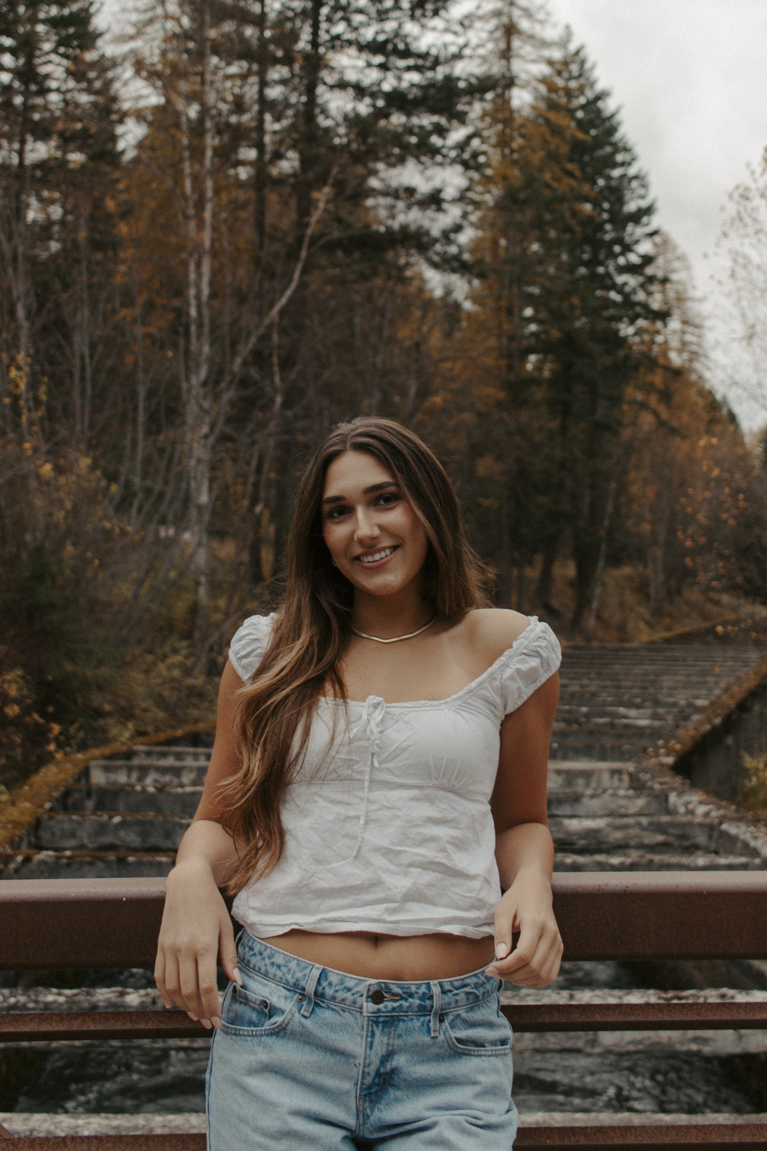 girl leans against rail in white shirt