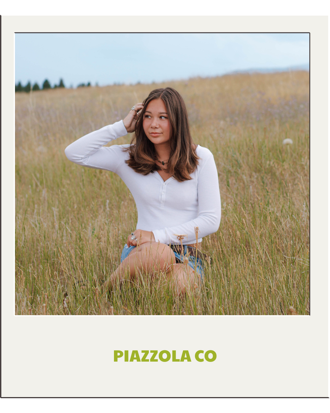 senior sits in grass and looks to the side