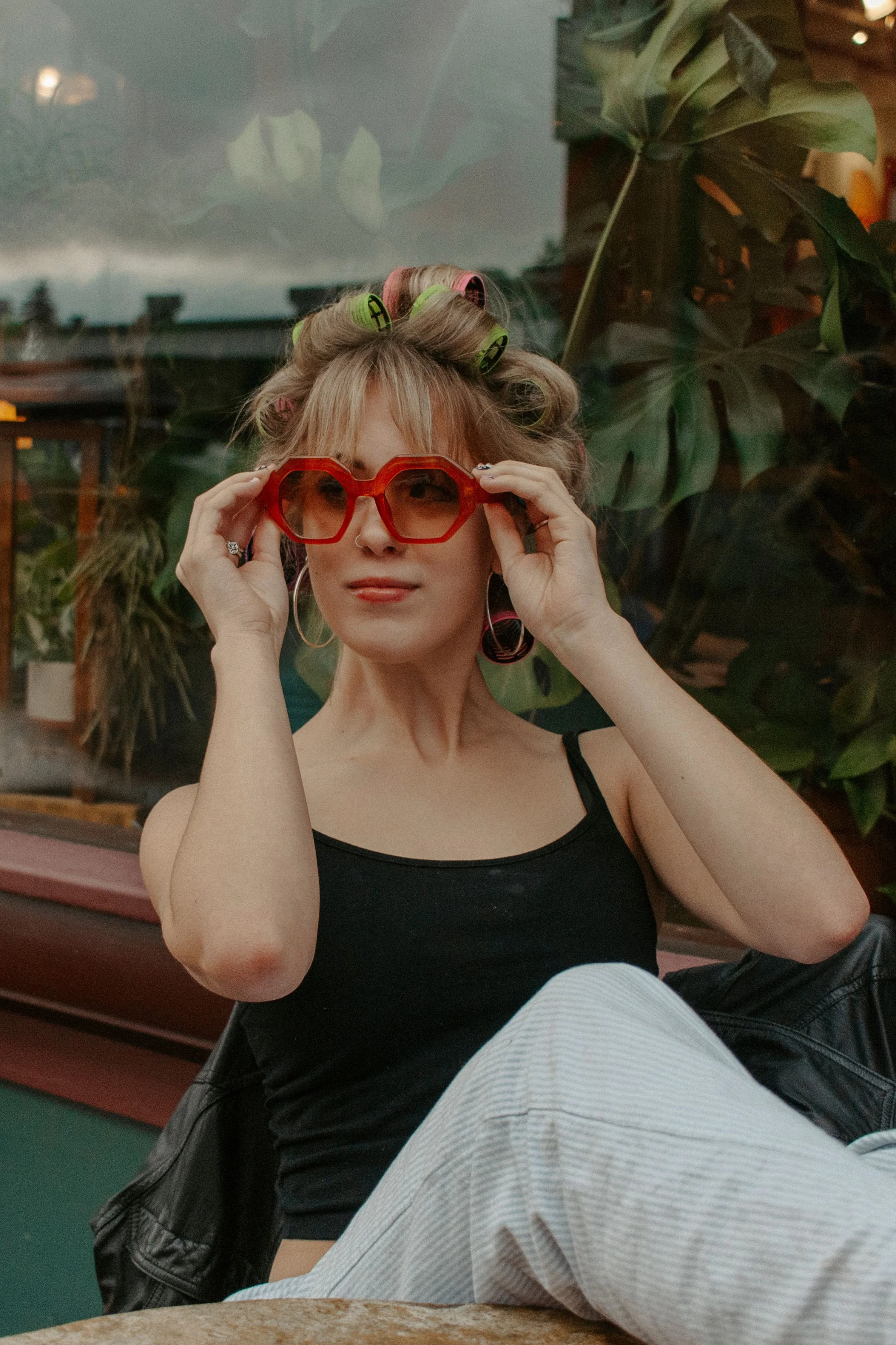 girl put on red glasses while sitting at table with legs up