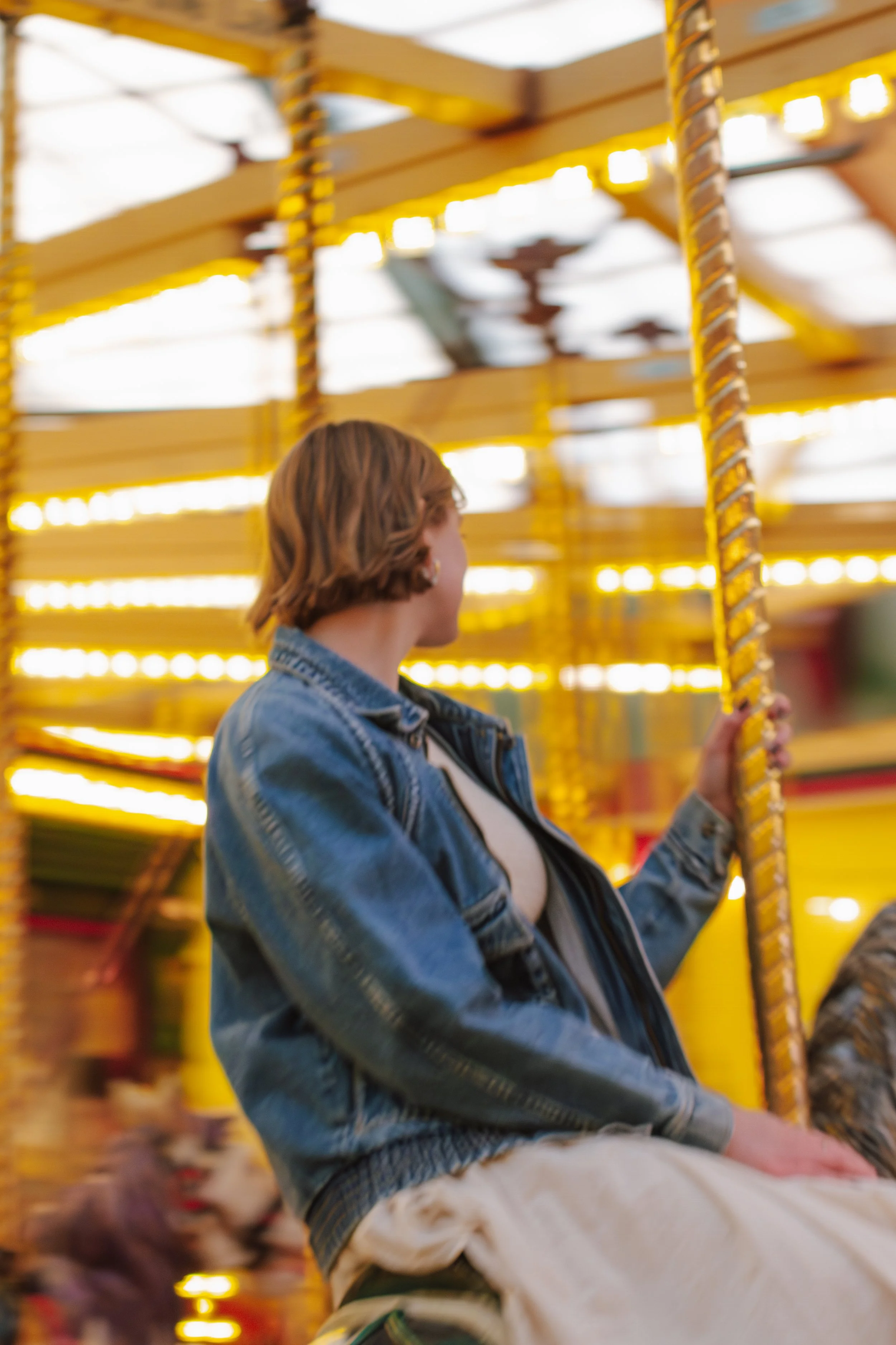 senior girl sits on carousel ride while its going