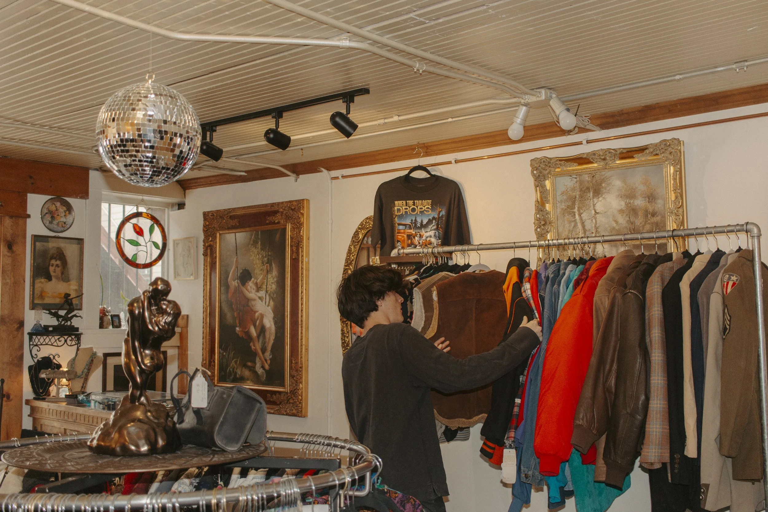boy looks through jackets at thrift store