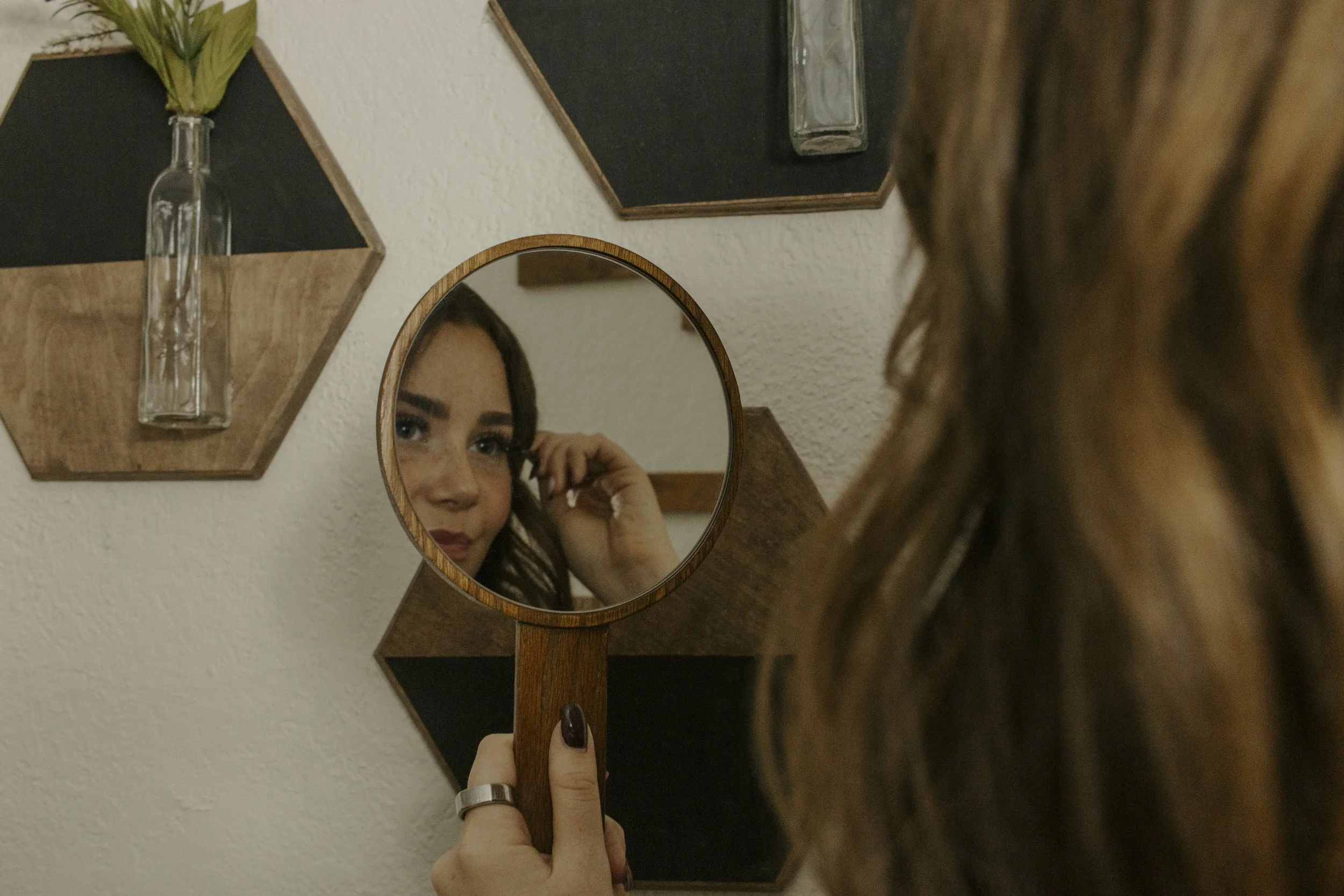girl brushes eyelashes in mirror