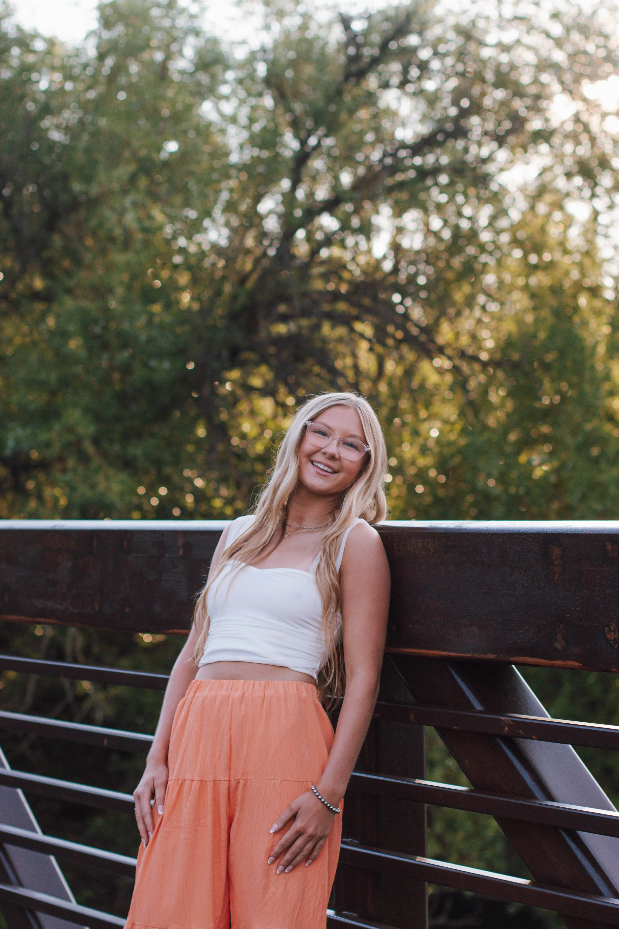 senior girl leans up against rail