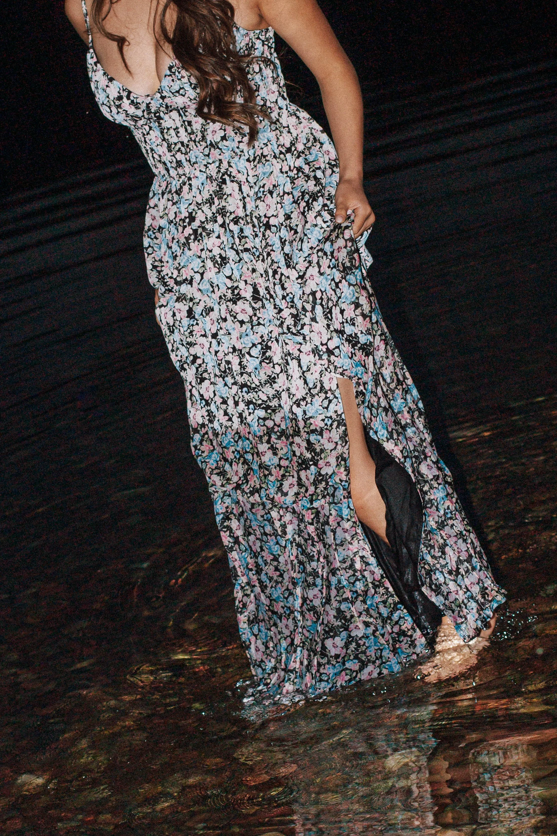 girl holds dress while walking through lake