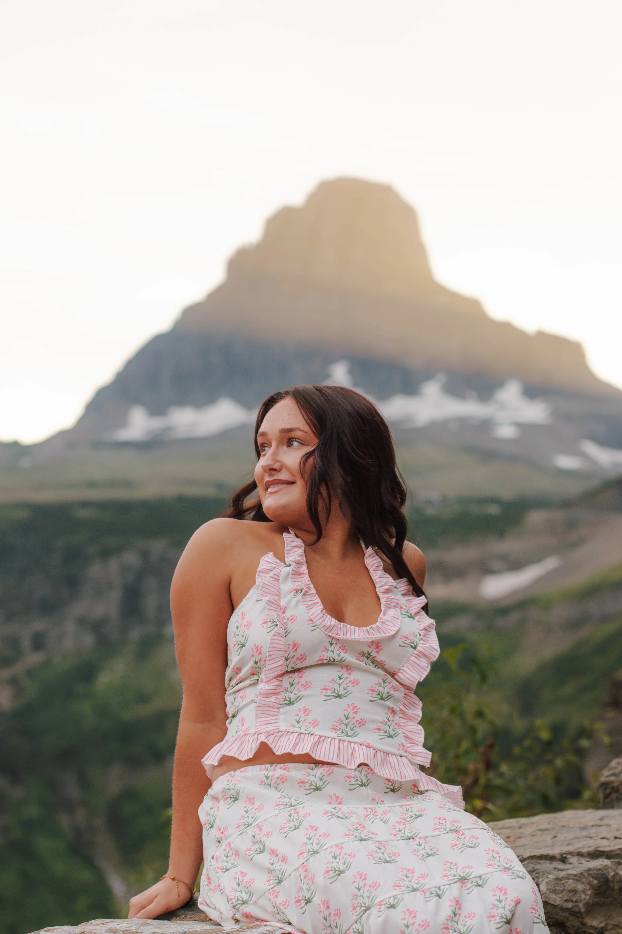 senior sits on rock in front of Glacier mountain