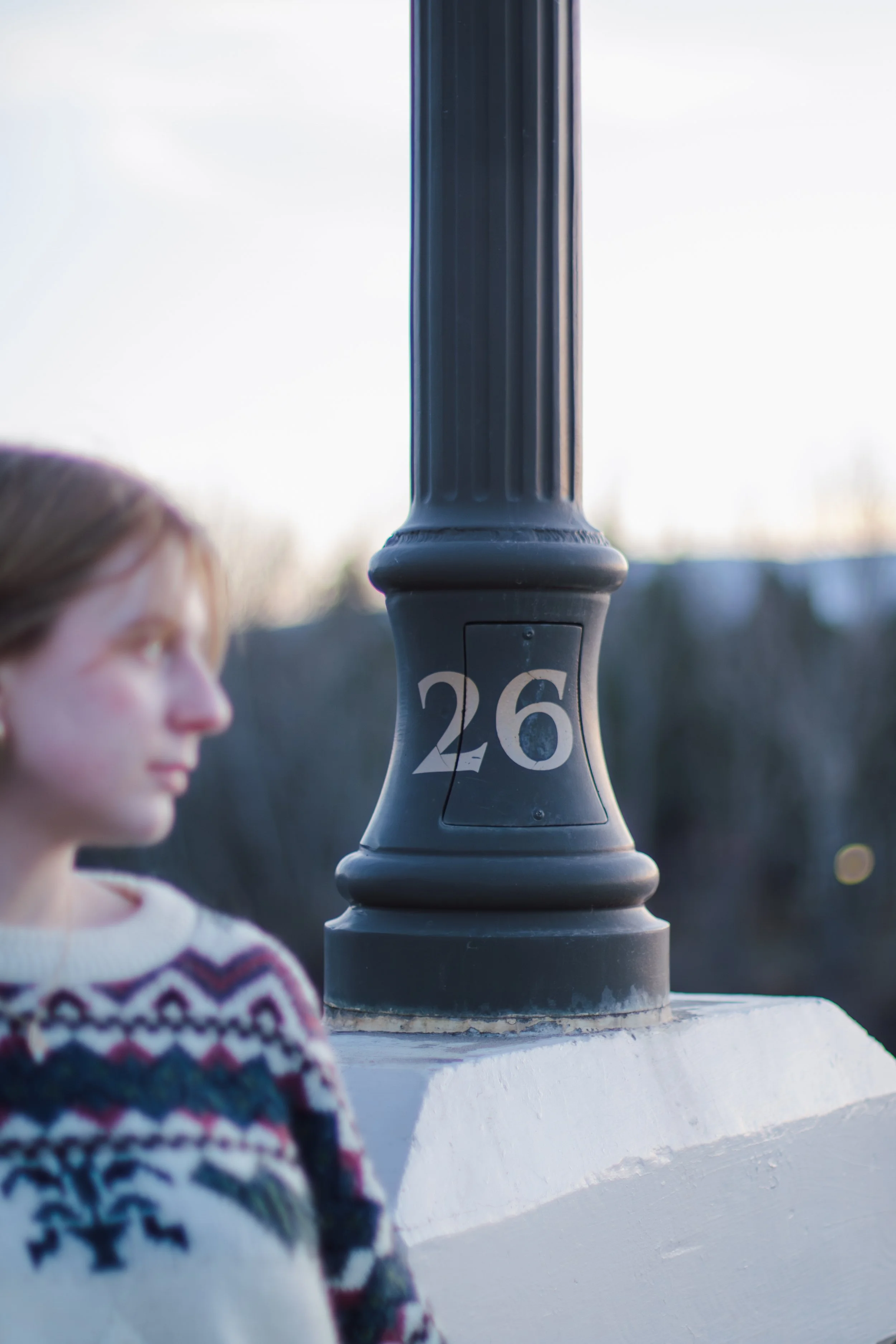 number 26 light pole with senior looking to the side in front of it