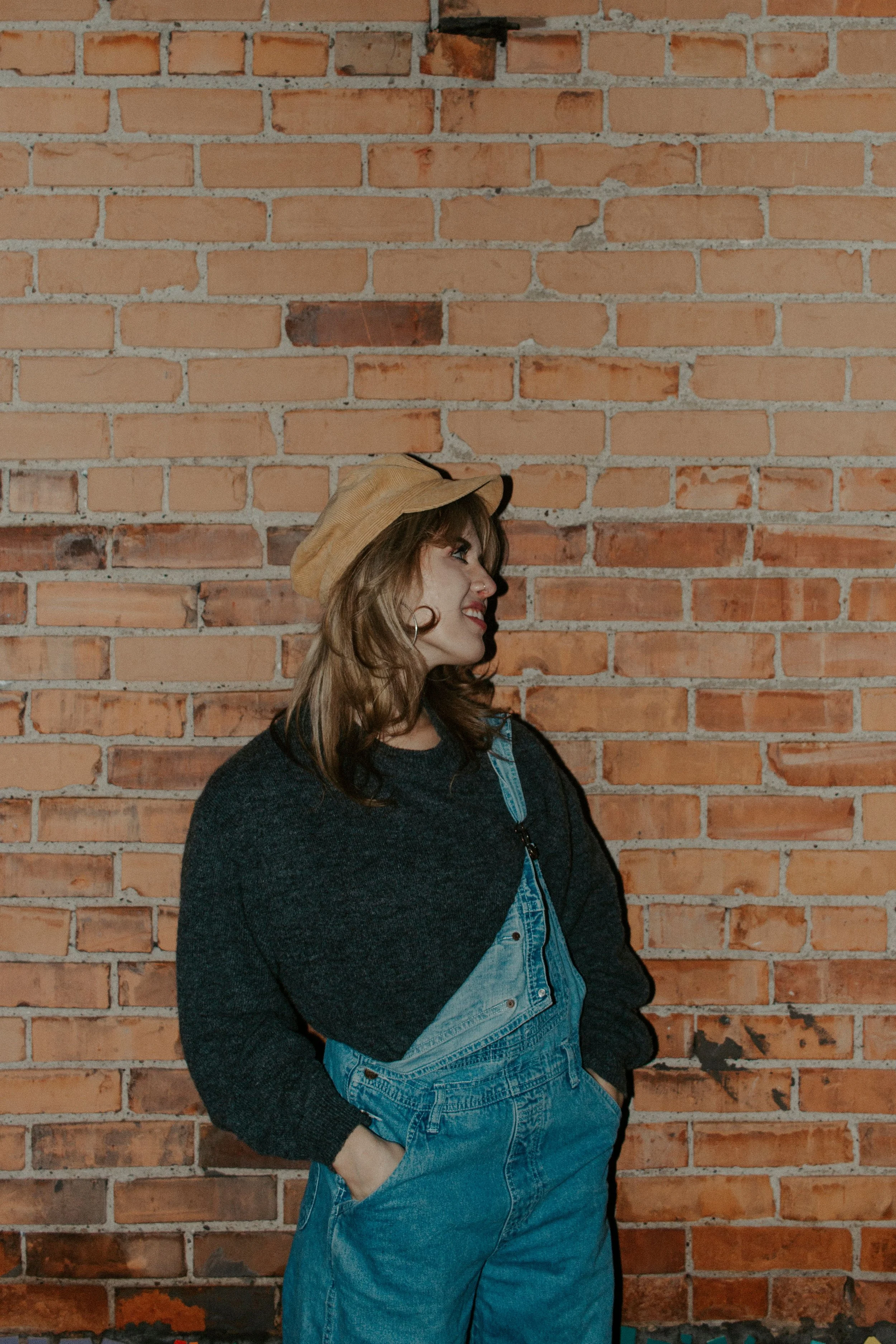 girl looks to the side in front of brick wall