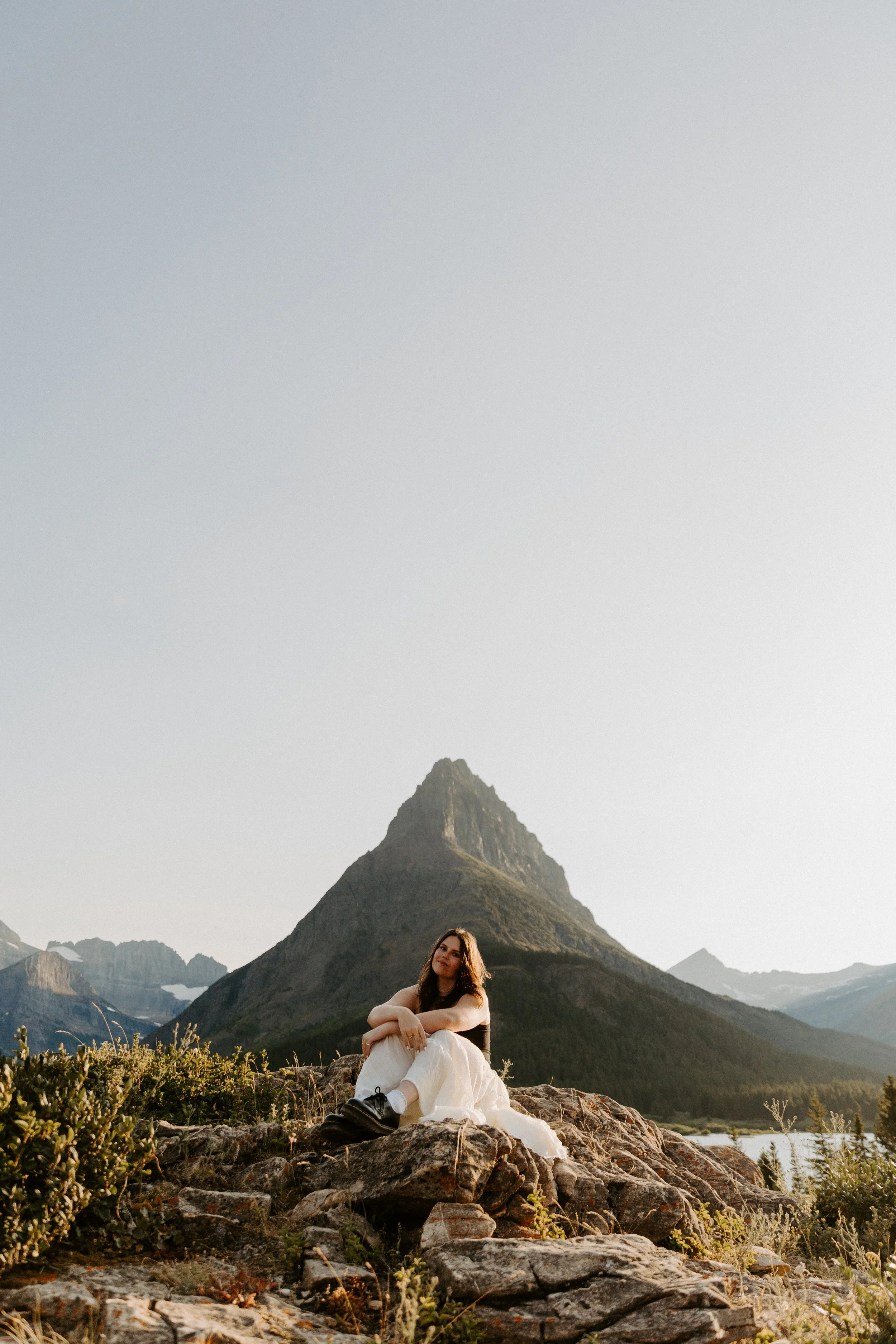 montana and destination photographer morgan piazzola sitting on rock in front of glacier mountain
