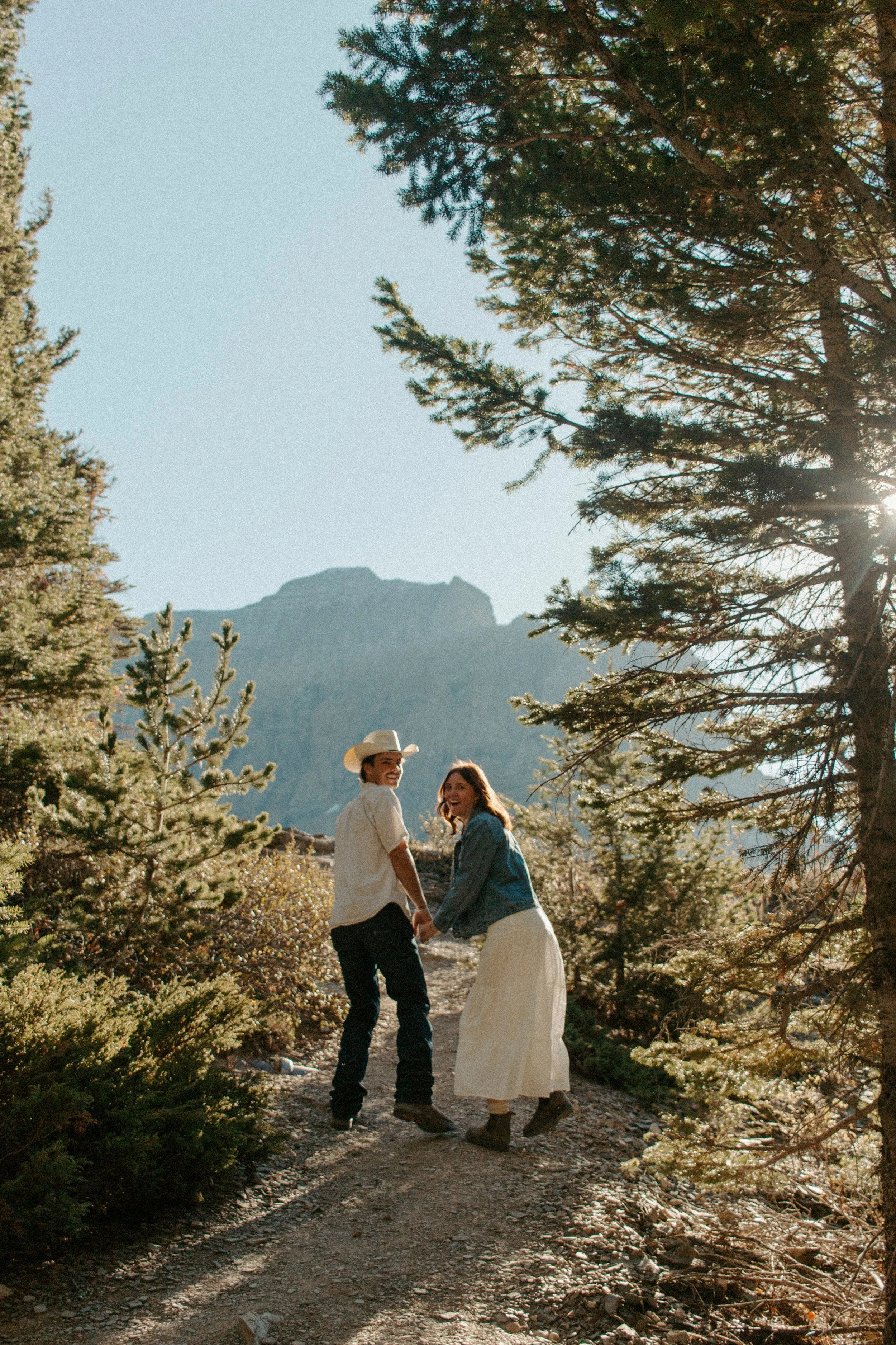 couple holds hands while walking up trail