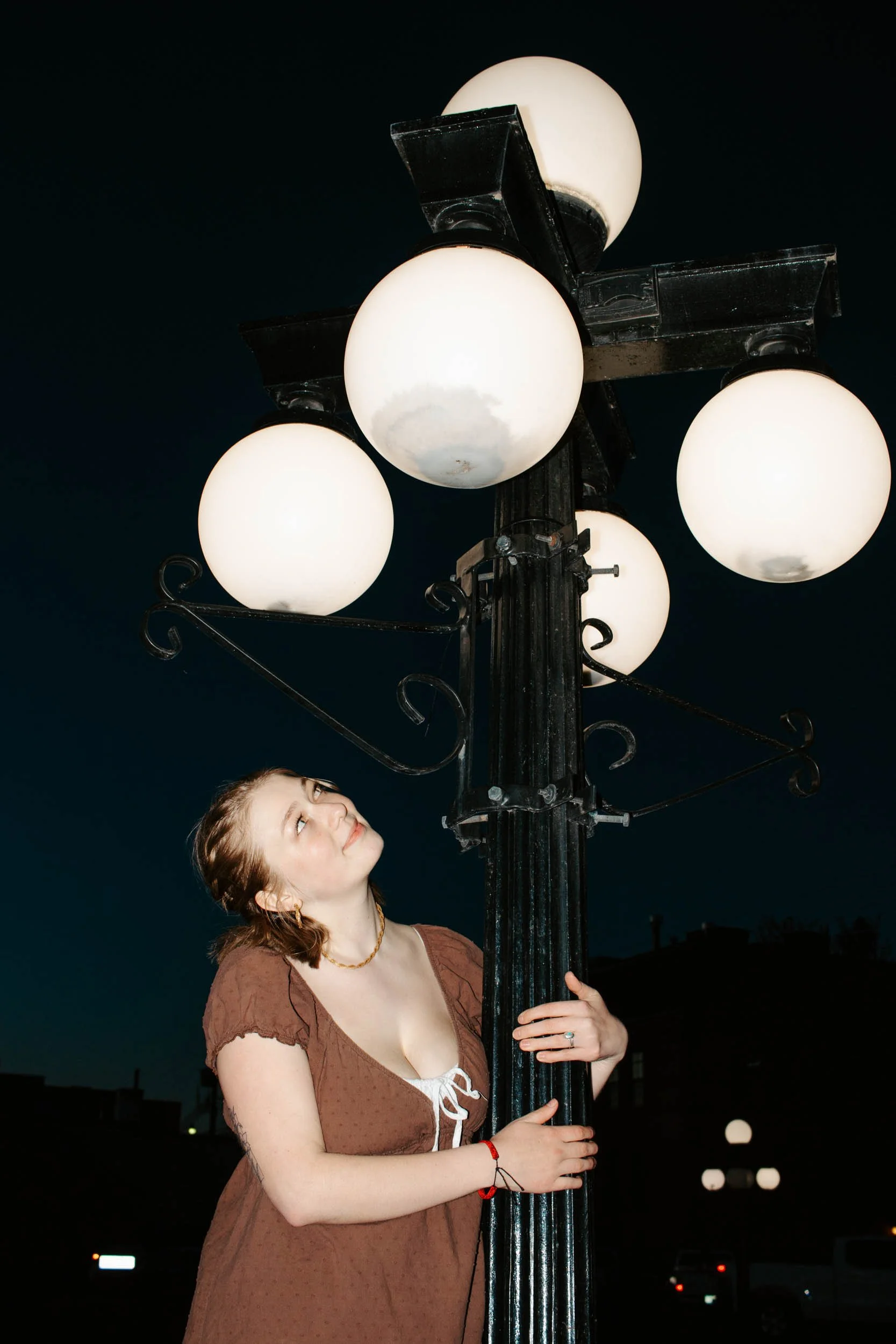 senior girl wraps arm around light post