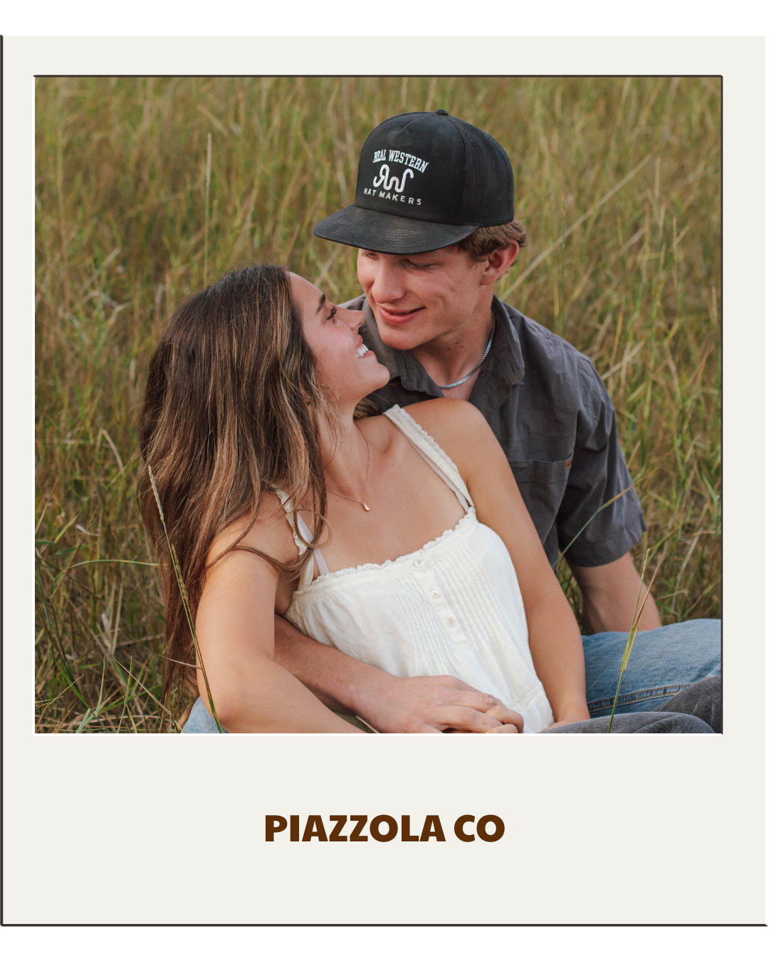 couple sits on grass and looks at each other