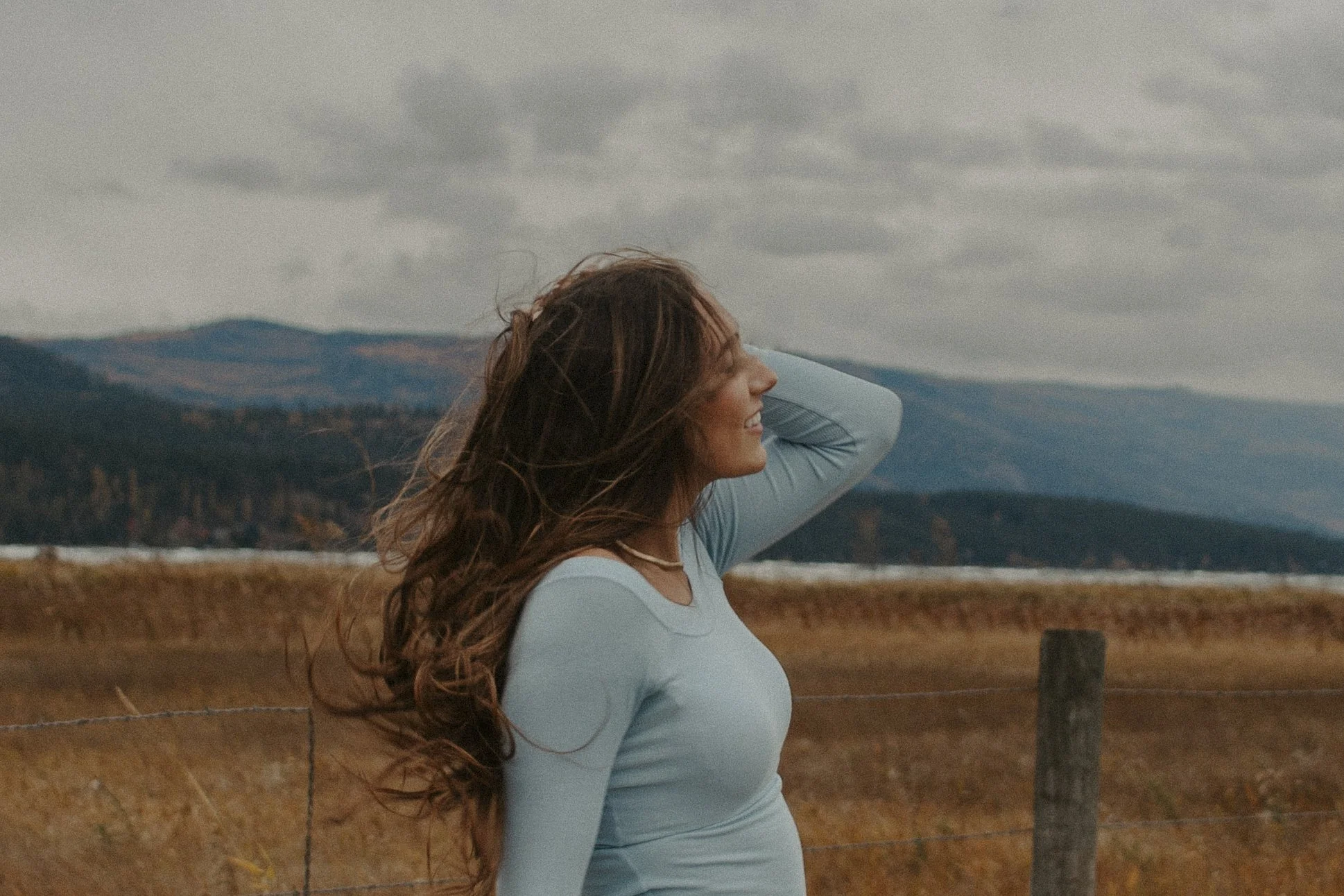 girl runs hands through hair in front of lake