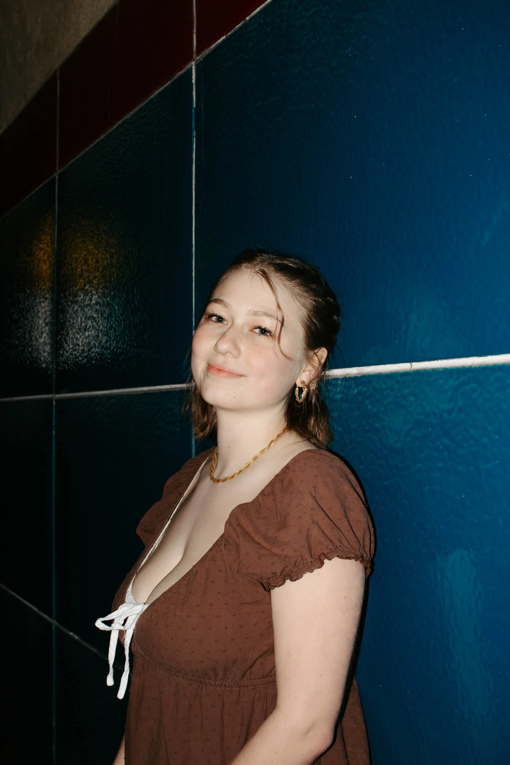 girl leans up against blue tiled wall
