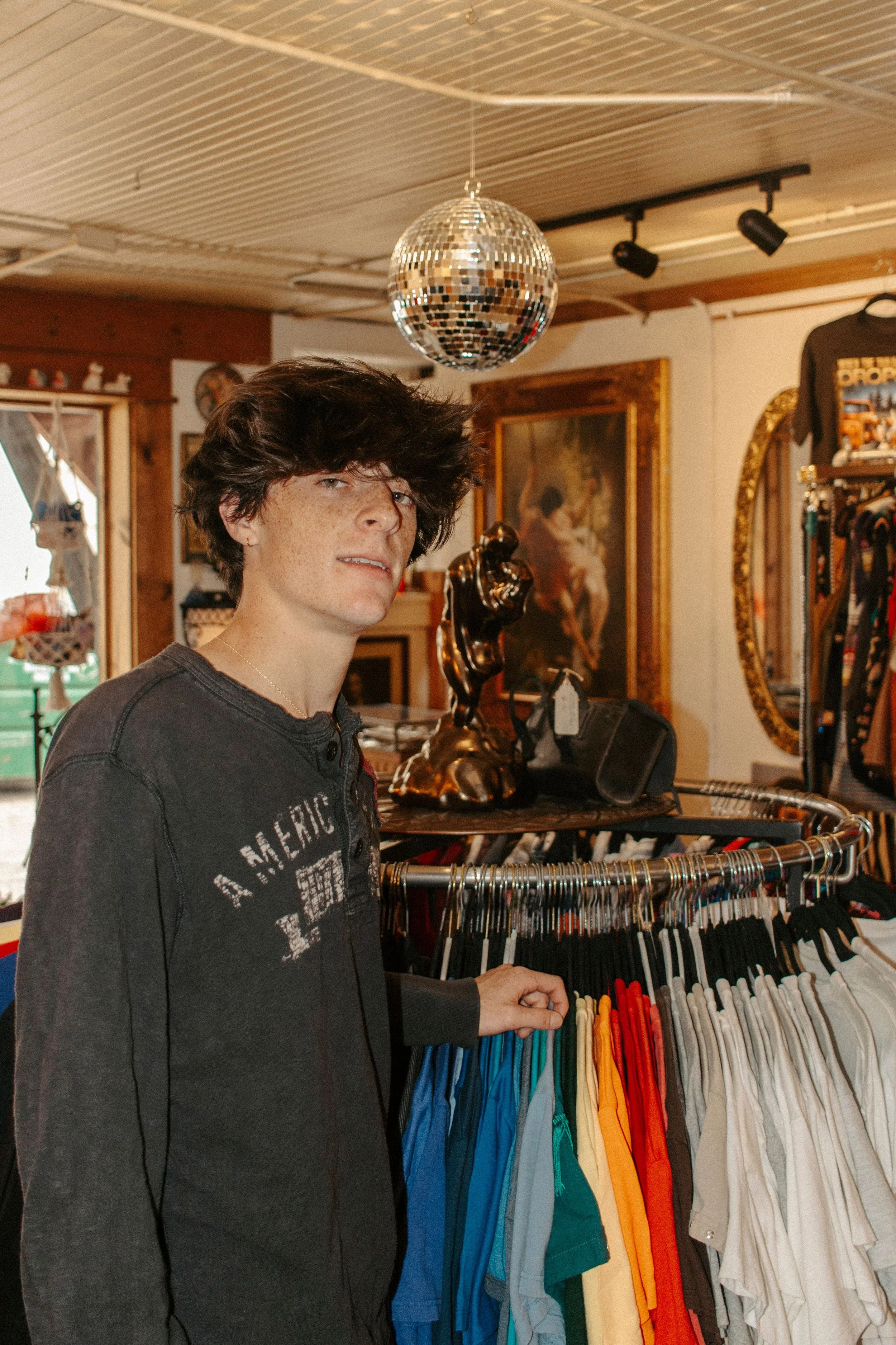 boy stands in front of clothing rack