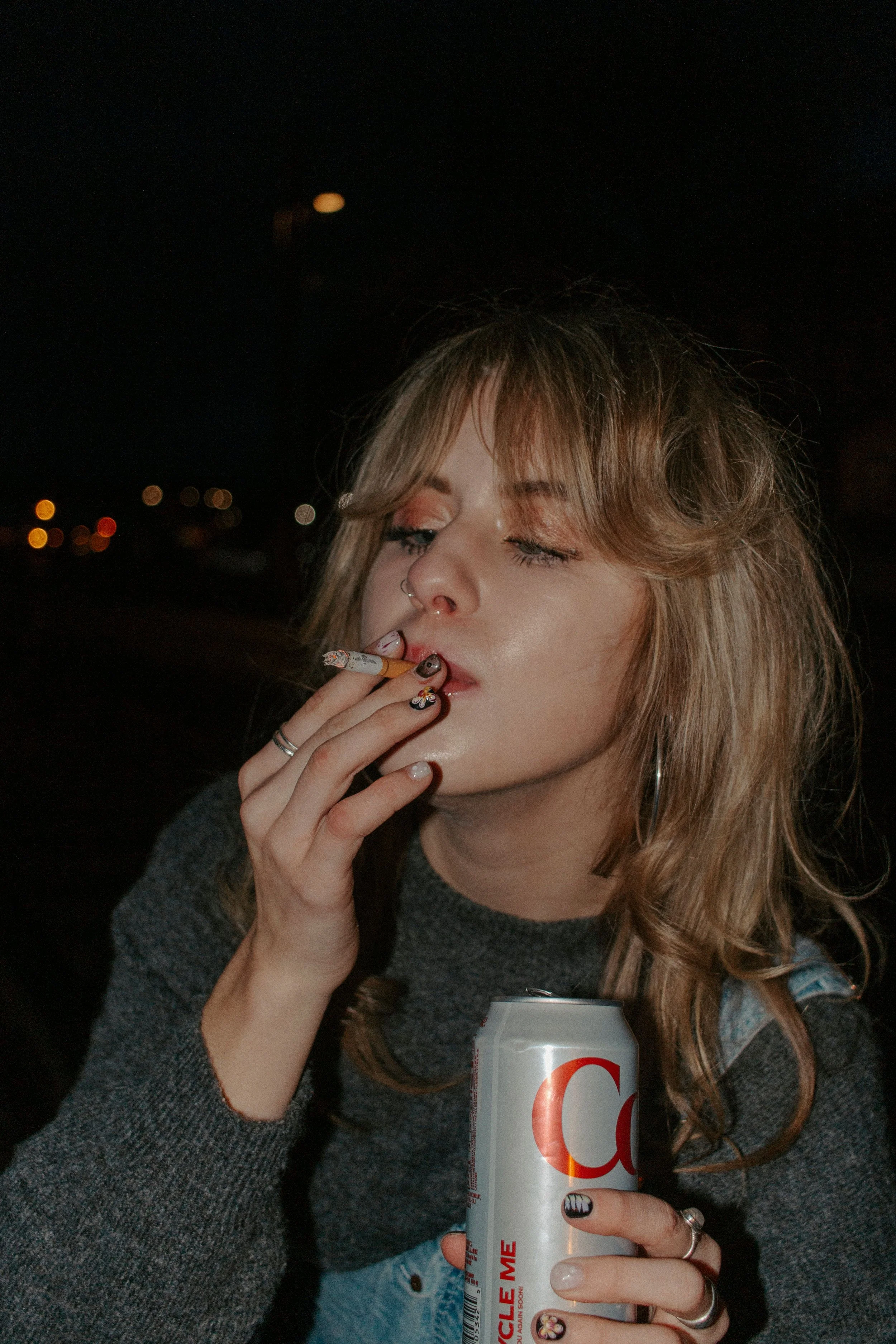 girl smokes cigarette while holding a diet coke